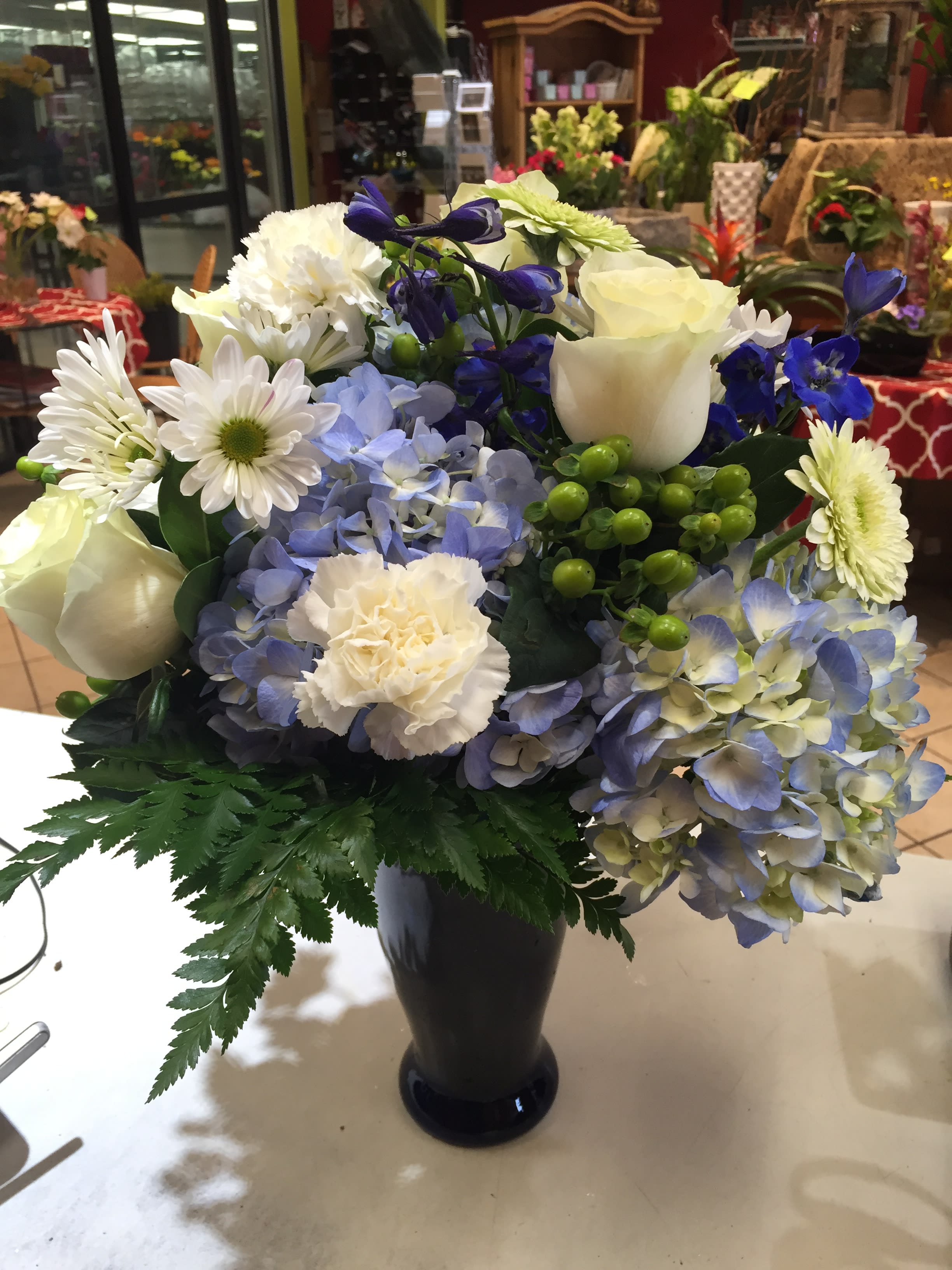 Blue and white mixed flower arrangement in a black vase