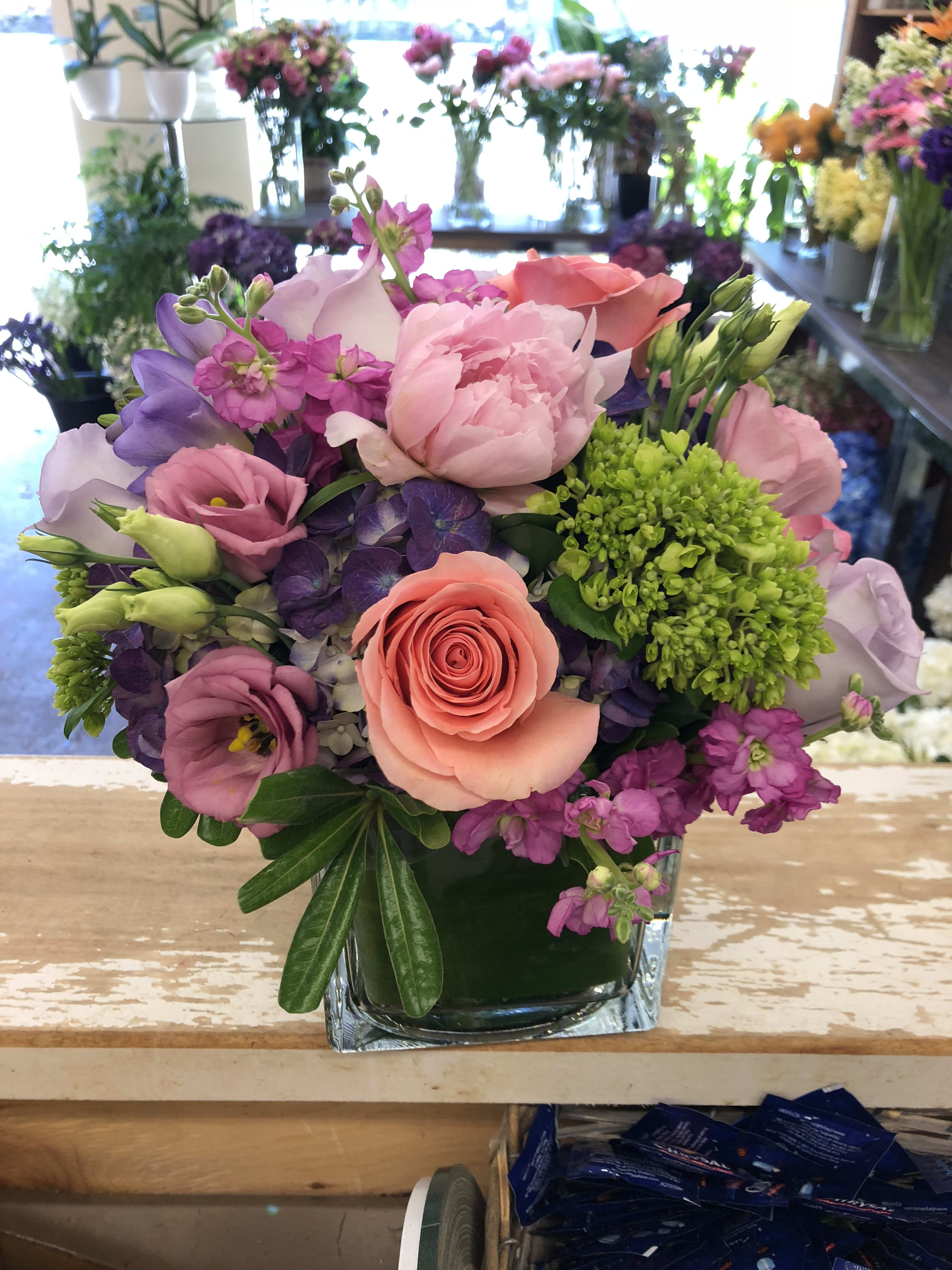 Mixed pink and purple bouquet in a square glass vase