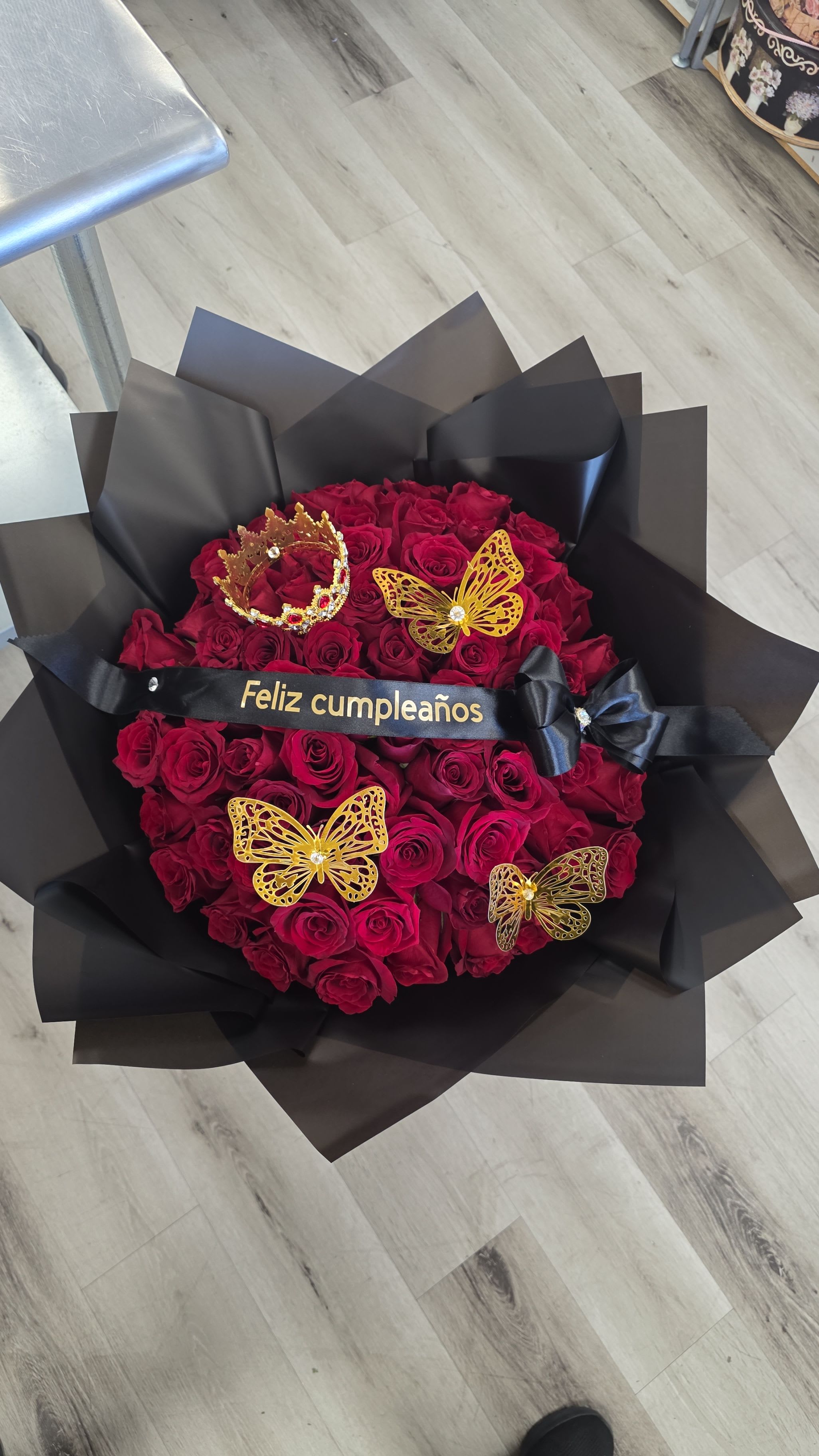 Bouquet of red roses wrapped in black paper with gold butterfly decorations