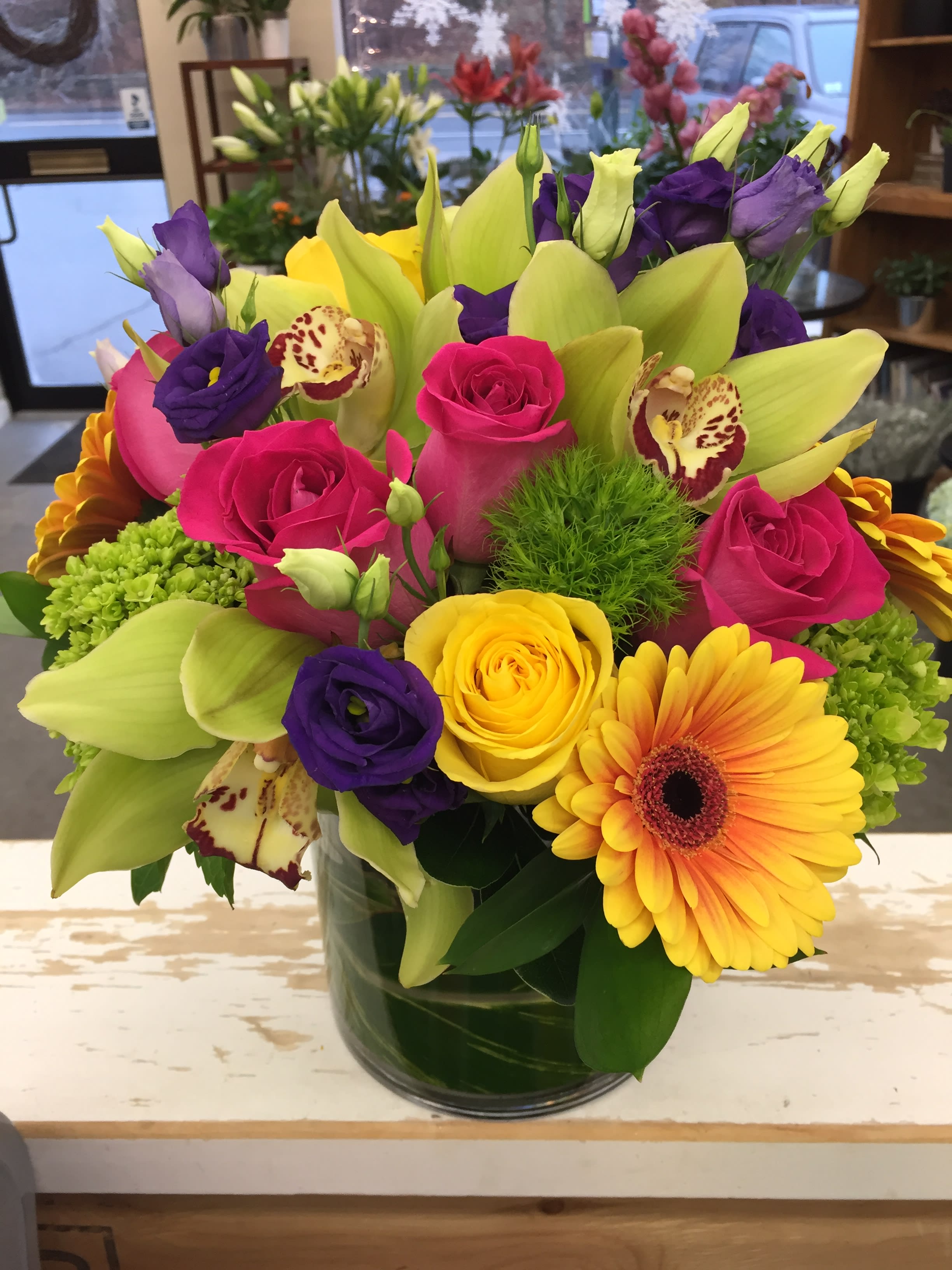 Colorful bouquet of roses, lilies, and gerbera daisies in a glass vase