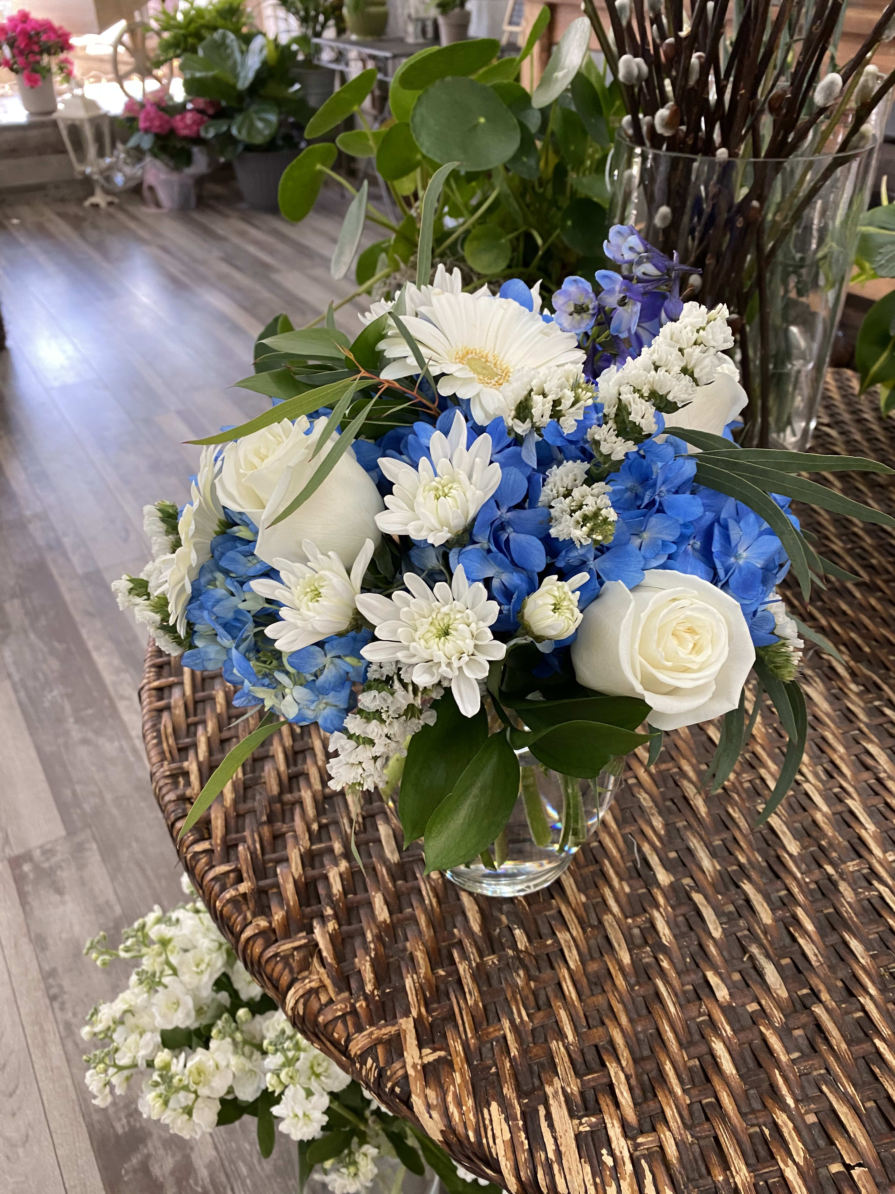 Blue and white flower arrangement in a clear glass vase