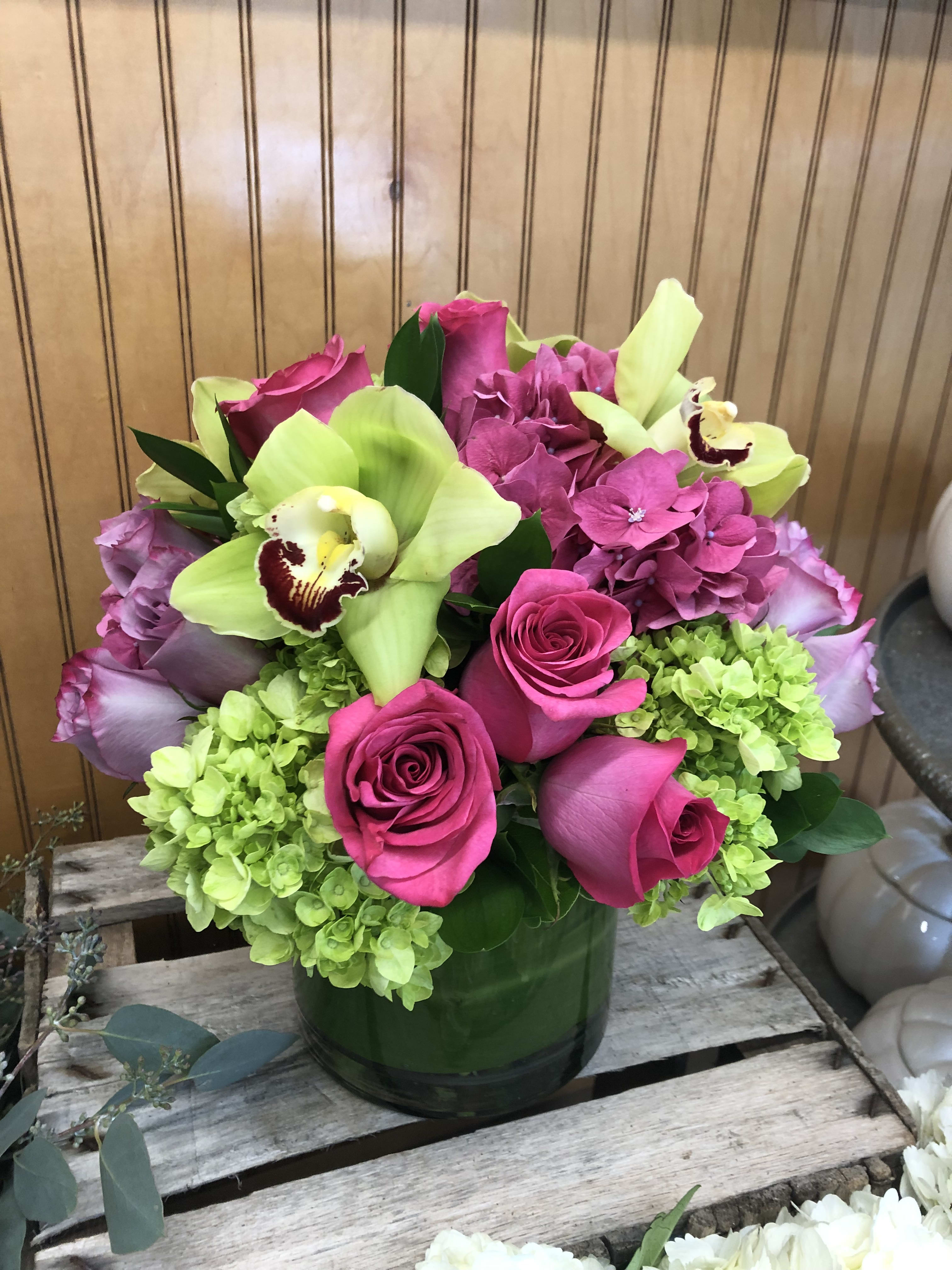Pink roses and green hydrangeas in a glass vase with pale green orchids