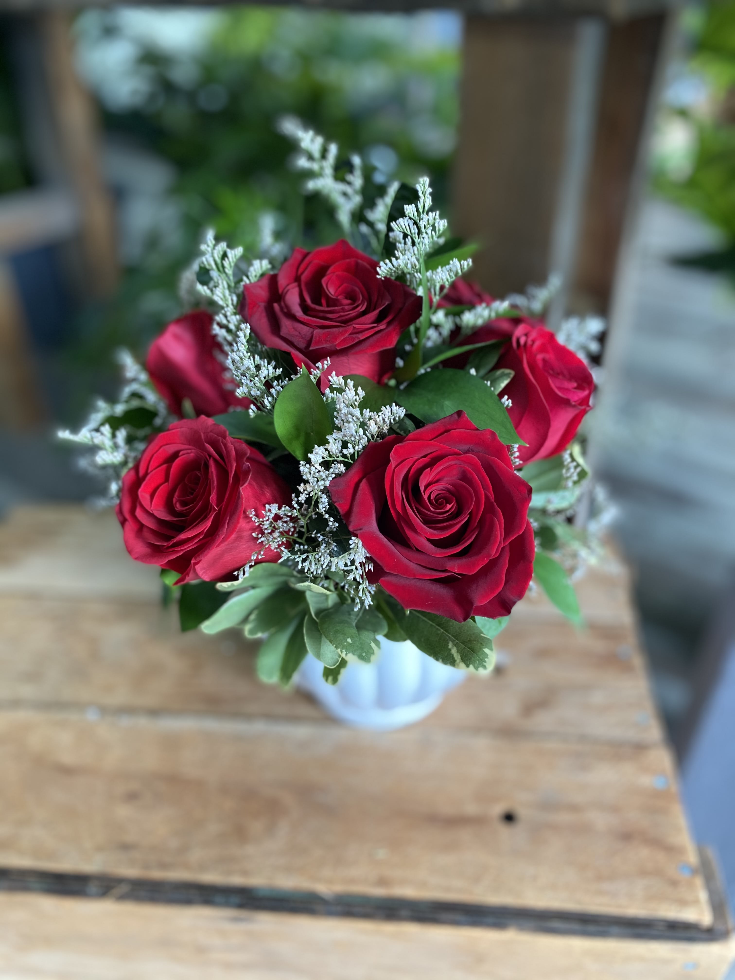Bouquet of red roses with white filler in a small vase