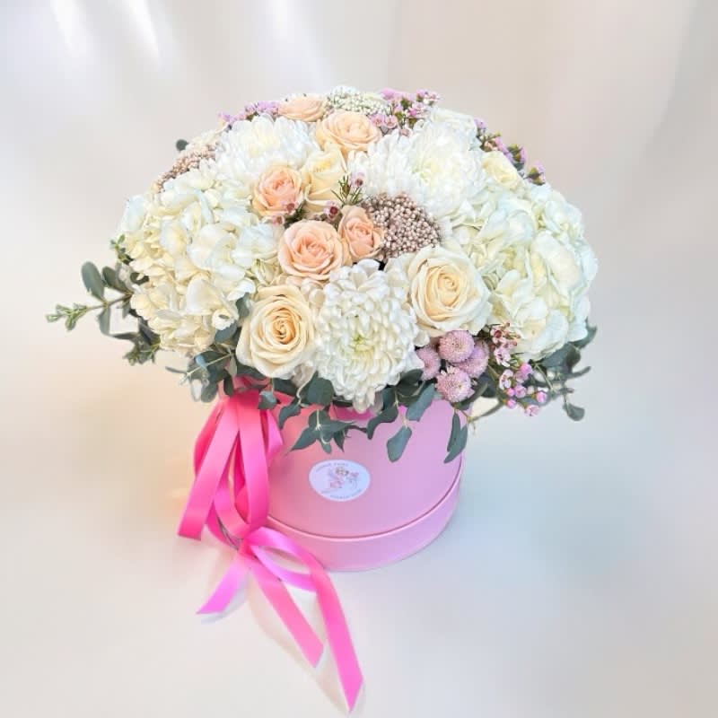 Round bouquet of white and blush flowers in a pink hat box with a ribbon