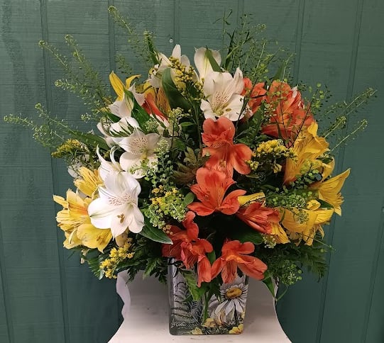 Mixed bouquet of white, yellow, and orange lilies in a decorative vase