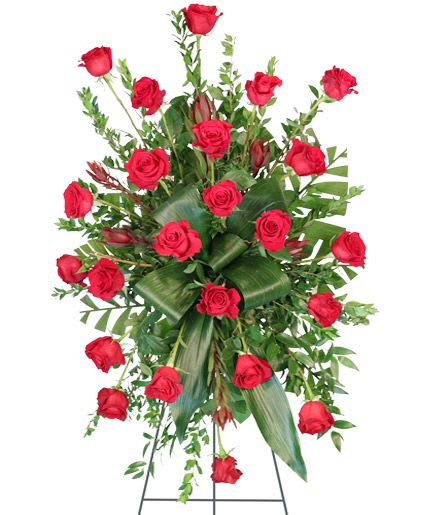 Crimson Departure Standing Spray - Send your loved one off with a truly classic standing spray filled with stunning red roses surrounding luscious foliage. The Crimson Departure standing spray is an elegant addition to any funeral service, memorial service, or wake.  Includes: Foliage: Myrtle, Aspidistra, Teepee, Salal, Red Roses, Safari Sunset Leucadendron
