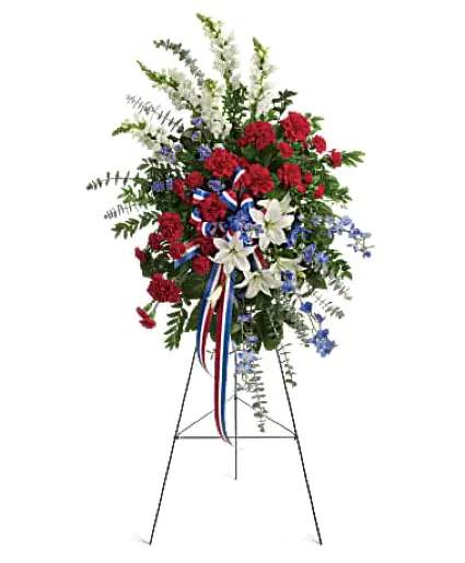 Veteran's Honor Veteran Sympathy - The perfect way to honor a veteran. This easel-mounted standing spray features flowers such as red carnations, white asiatic lilies and snapdragons, and blue delphinium, along with an assortment of greens.