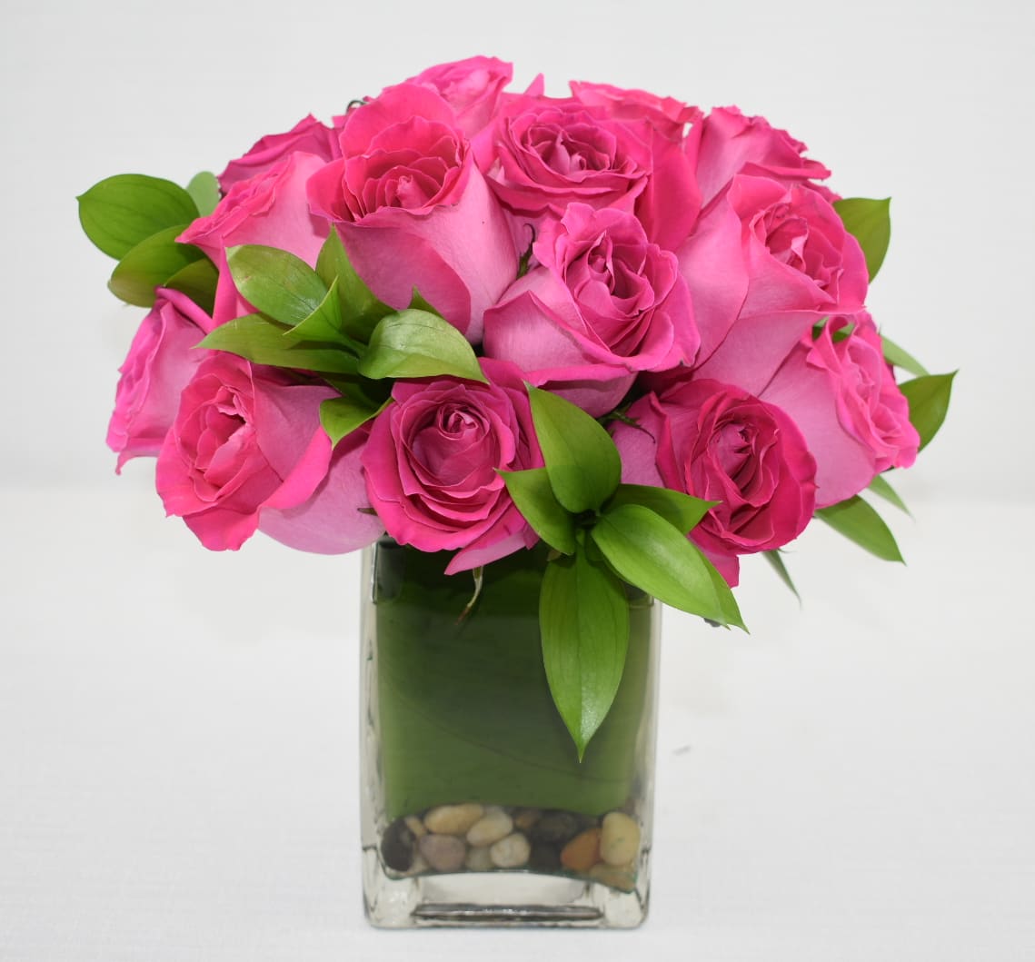 Bouquet of bright pink roses in a square glass vase