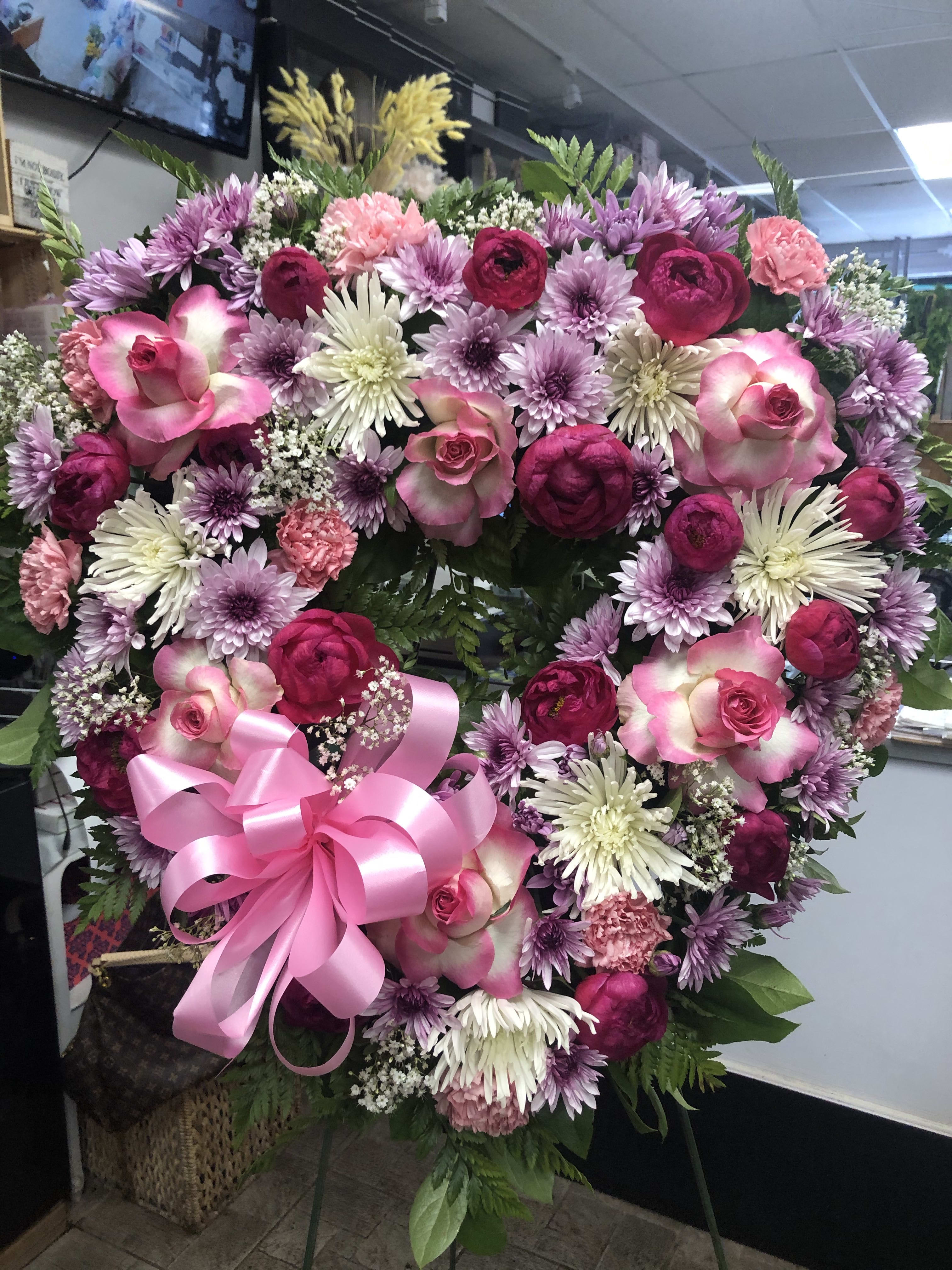 Heart-shaped floral wreath with pink and purple flowers and a pink ribbon bow