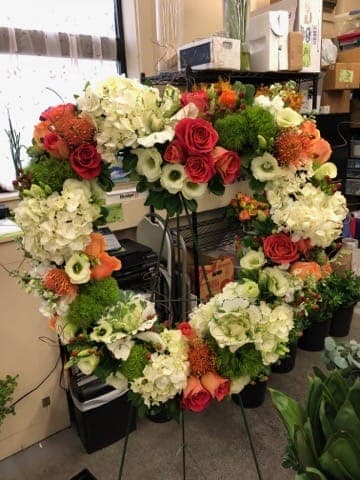 Large floral wreath with red roses, white hydrangeas, and orange blooms