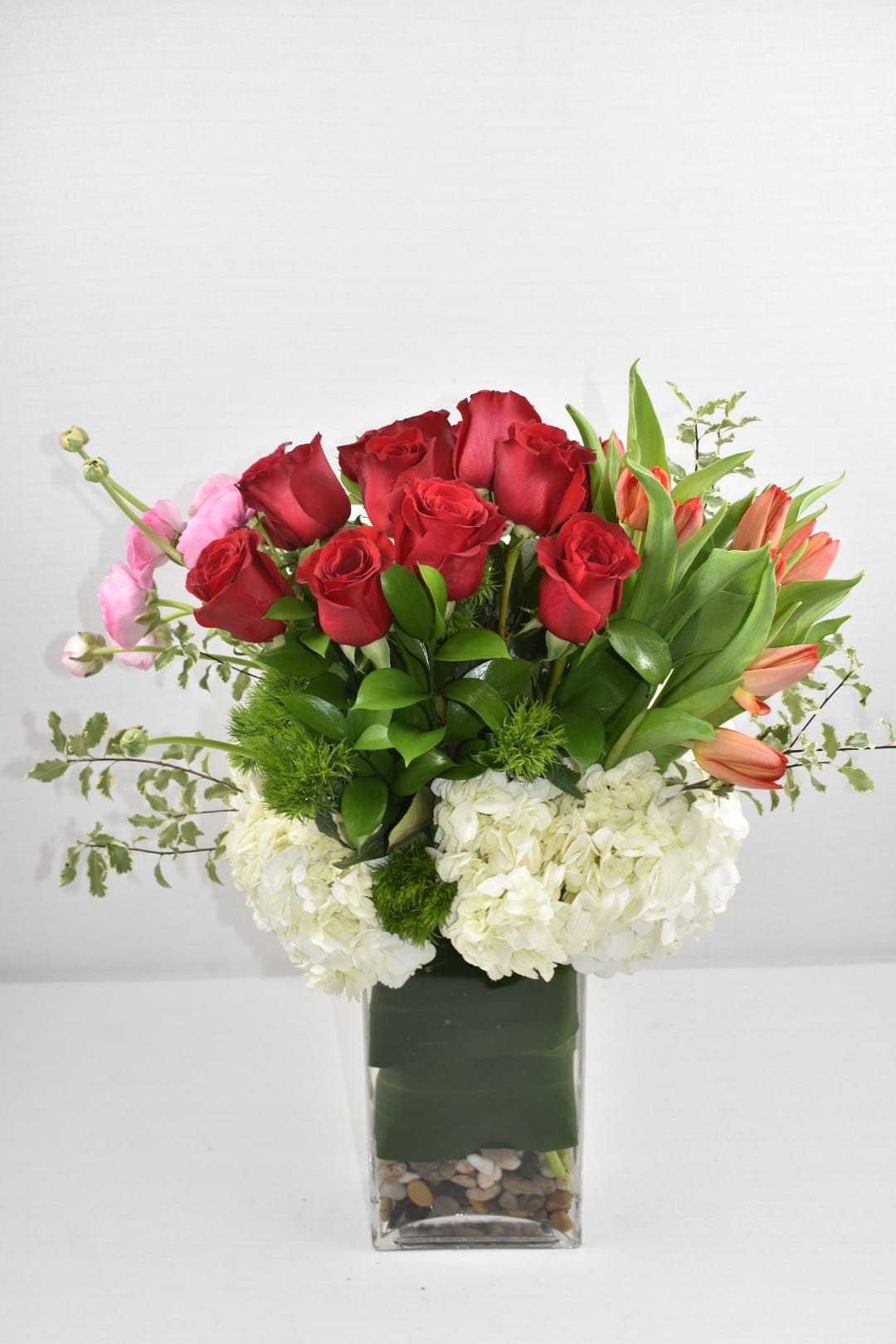 Feel The love  - Does she like roses and tulips? This is the perfect  arrangement Comes in a rectangular vase with 2 dozen of Ecuadorian Red roses on one side it has red tulips in the other side pink rannunculus  perfectly combined with white hydrangeas and greenery 