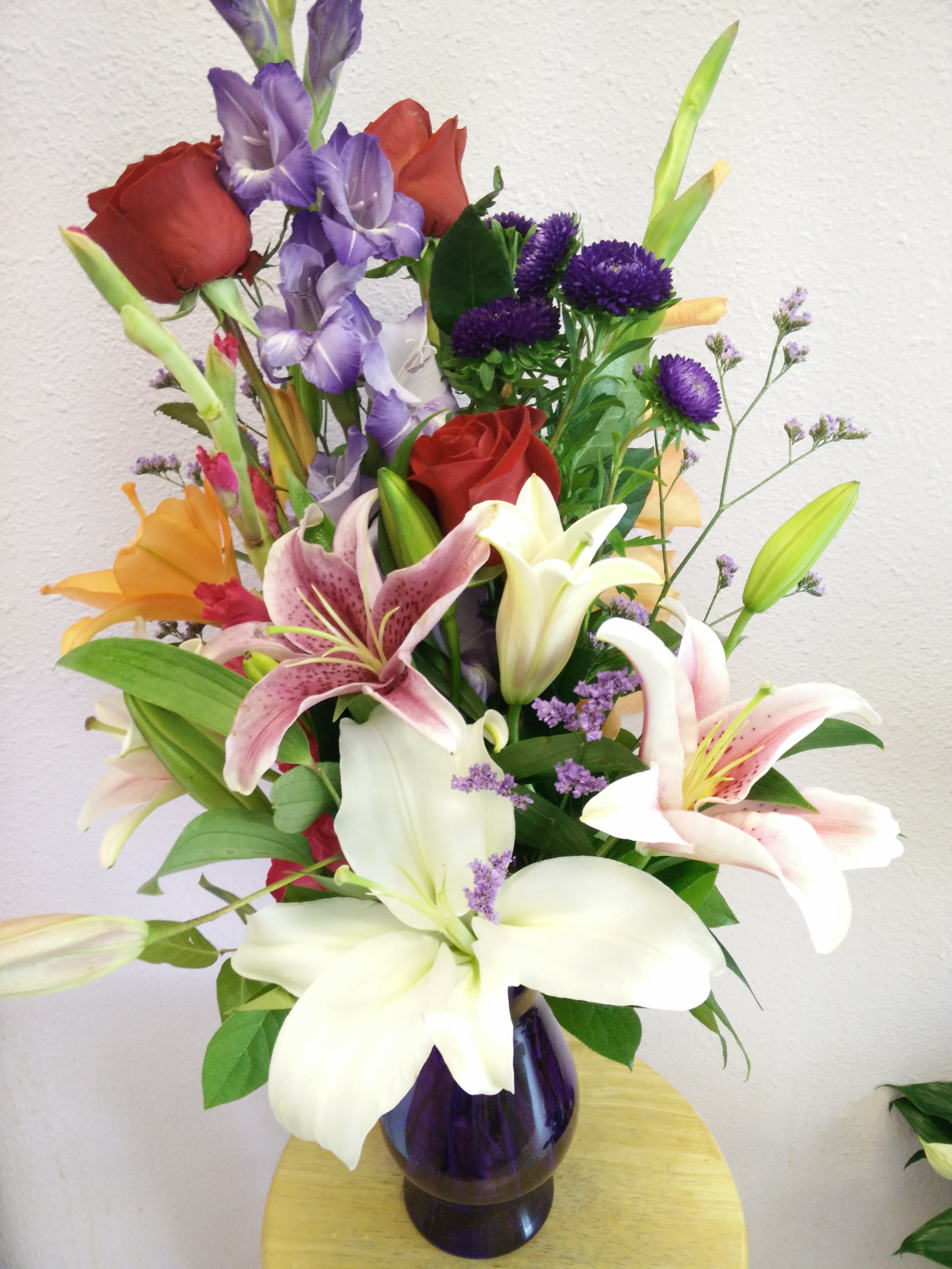 Milestone Memories By Forever Flowers - Red Roses, purple Matsumoto Asters, Gladiola, Star gazer, Asiatic, and oriental Lilies.