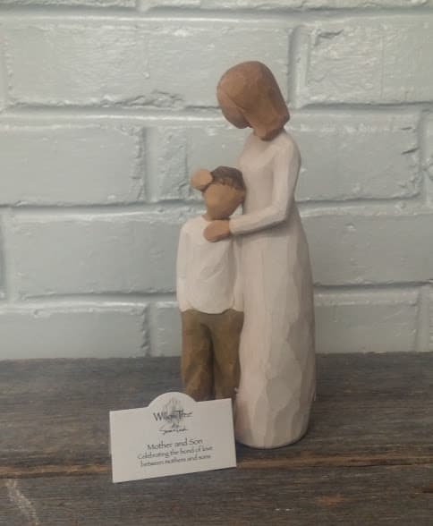 Wooden figurine of a mother holding a child, with a small product card in front