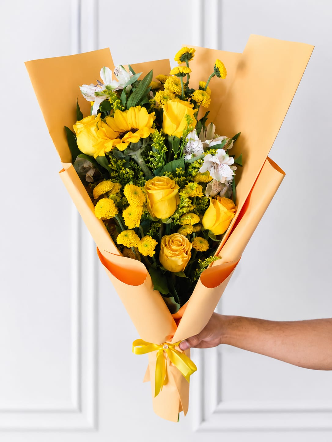 Sunshine bliss arrangement  - cheerful hand-tied bouquet featuring vibrant yellow roses, a sunflower, white alstroemeria, yellow button chrysanthemums, solidago, and fresh greenery, elegantly wrapped in premium peach paper with a satin ribbon. Perfect for birthdays, congratulations, get well wishes, anniversaries, or simply brightening someone's day.