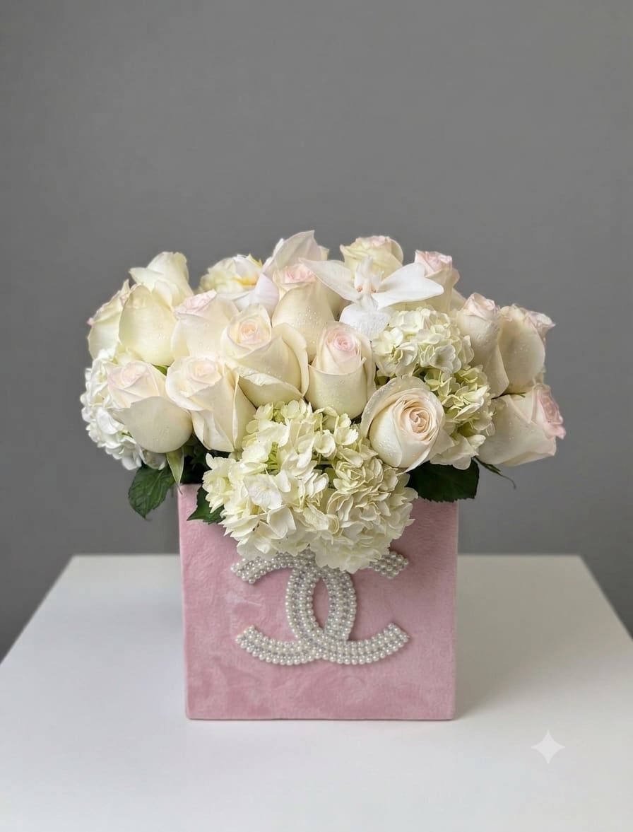 Pink princess - Cream and blush roses tucked among pale hydrangea blooms create an irresistibly soft impression in this floral arrangement - a birthday bouquet, anniversary gift, or Mother's Day surprise that reads pure romance. The flower arrangement arrives gift-ready in a square pink decorative box, the low, dense styling keeping the focus on the petals so the person you're celebrating feels truly noticed.  Cream and pink roses pair with pale green-tinted hydrangeas for a creamy, feminine palette; blooms are tightly packed for a lush, garden-fresh look and sit securely in the velvet-like pink box. A subtle pearl-studded logo on the front adds a refined, luxurious touch without distracting from the flowers, making this a polished choice for weddings or any moment you want to mark with elegance.  Perfect for someone who prefers understated glamour, this piece sends a message of tenderness and thoughtfulness - the kind of gift that makes her feel cherished. The low-profile box makes it easy to display on a table or mantel; order with standard delivery for same-day options when available.