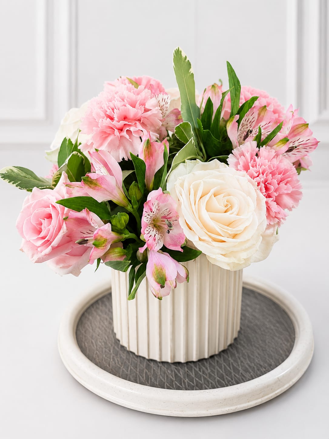 Candy blooms  - A graceful floral arrangement featuring premium white and blush pink roses, soft pink carnations, delicate alstroemeria, and fresh greenery, beautifully designed in a modern ribbed ceramic vase. Its romantic pastel tones make it perfect for birthdays, anniversaries, baby showers, thank-you gifts, sympathy, or simply brightening someone's day.
