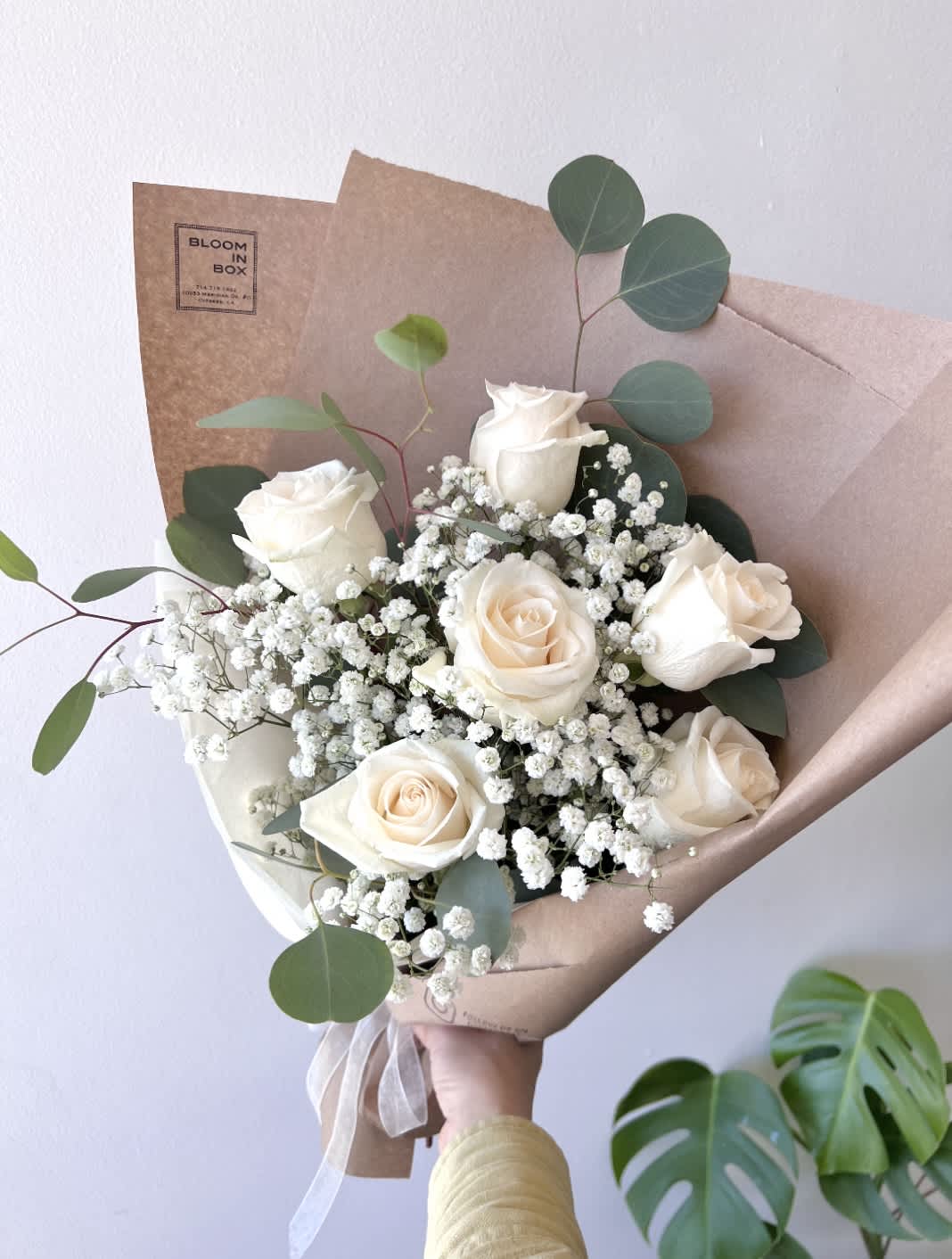 Bouquet of white roses with baby's breath and eucalyptus in brown paper