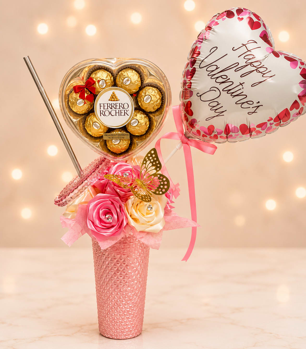 Thermos with eternal flowers and chocolates - A playful, romantic gift that feels like more than a bouquet - this flower arrangement pairs silk roses and a heart-shaped Ferrero Rocher chocolate box with a Valentine's Day heart balloon for an unforgettable anniversary or Valentine's Day surprise. As a Valentine's Day gift or romantic treat, it reads as cheerful and celebratory: the recipient will feel adored the moment they see the pink textured vase topped with lively faux blooms and a fluttering butterfly pick.  The arrangement mixes silk roses in pink, white and red tones, accented by a gold-wrapped chocolate centerpiece and a small heart-shaped foil balloon. Presented in a tactile pink textured thermos-style vase tied with a pink ribbon, the display includes a heart-shaped chocolate box, a decorative butterfly pick, and a metal straw for a modern, keepsake-ready look. The gold chocolates add a warm metallic pop against the soft florals for a bright, joyful palette.  Perfect for the person you want to make feel truly seen on Valentine's Day, an anniversary, or just-because celebration, this set arrives ready to display - no water or floral care needed since the roses are silk. The compact, gift-ready composition fits easily on a bedside table or desk and ships as shown for immediate gifting impact.