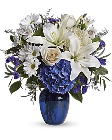 White lilies and daisies with blue hydrangea in a blue vase