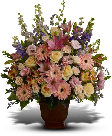 Mixed pink and cream flowers arranged in a brown urn vase
