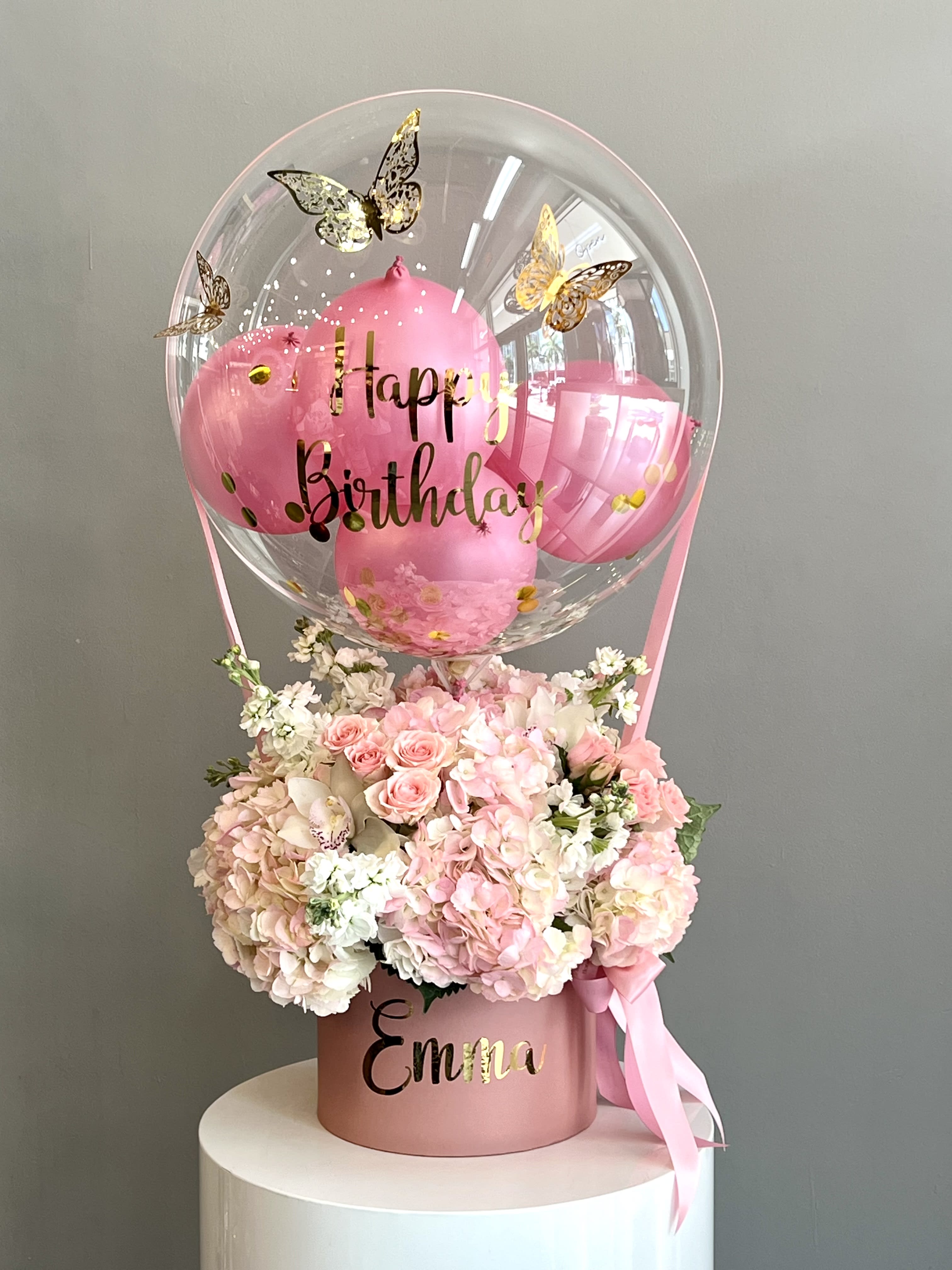 Pink birthday balloon above a pastel flower arrangement in a pink box