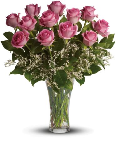 Arrangement of pink roses with white filler flowers in a clear glass vase