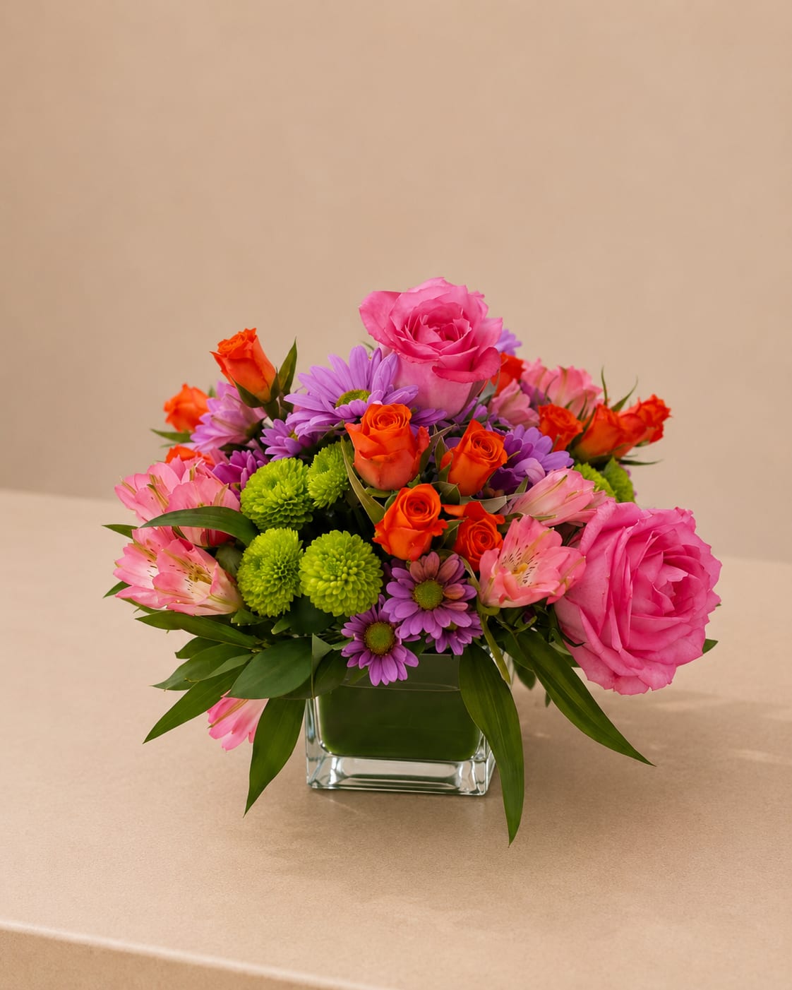 Colorful Floral Cube - A vibrant and cheerful flower arrangement featuring a beautiful mix of pink and orange roses, fresh seasonal blooms, and lush greenery, thoughtfully designed in a modern glass cube. Bursting with color and joy, this design brings warmth, energy, and a fresh, contemporary touch to any space.  Each arrangement is Designer’s Choice, carefully created with fresh seasonal blooms. Flower varieties and color tones may vary based on availability while preserving the overall style, palette, and quality.  Perfect for Mother’s Day, birthdays, thank you gestures, get well wishes, congratulations, or a bright and joyful “just because” surprise.  Same day flower delivery available in Southwest Florida, including Naples, Bonita Springs, and Fort Myers Beach. 