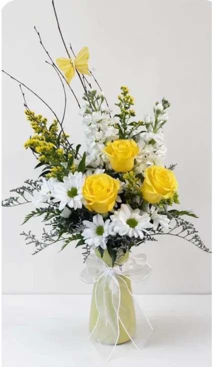 Simple Joy Flower Arrangement - This arrangement feels like a little burst of sunshine. The bright yellow roses bring warmth and happiness, while the crisp white daisies add a soft, cheerful balance. Light, airy greenery and delicate accents give it a fresh, just-picked feel, and the gentle butterfly detail adds a touch of whimsy. Altogether, it’s simple, bright, and uplifting—like a quiet moment of joy sitting beautifully in bloom.