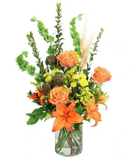 Vivid Sunset Floral Design - Bring the beauty of the setting sun indoors with this striking arrangement! The stunning orange roses, lilies, and yellow button poms contrast gorgeously against the lovely greenery, making Vivid Sunset a striking image. This delightful bouquet is perfect for any occasion!  Includes: Milk Jug Vase , Dried Wheat , Grapevine Balls , Myrtle, Solidago, Salal , Bells Of Ireland , Orange Lilies, Yellow Button Poms, Orange Roses.