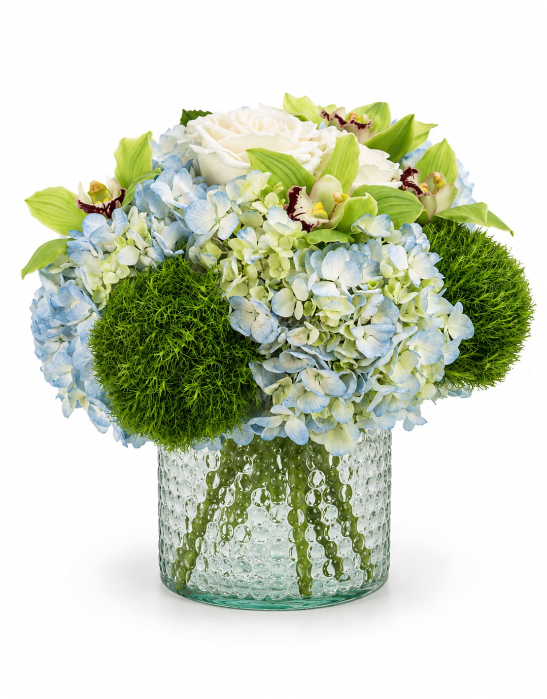 Blue Haven Luxe - Blue Haven Luxe is a fresh and graceful floral arrangement designed with soft blue hydrangeas, creamy white roses, green cymbidium orchids, and lush green dianthus for a look that feels peaceful, polished, and refined. Designed in a textured round glass cylinder vase, this arrangement brings together cool blue tones, crisp whites, and vibrant greens for a clean, modern presentation.  Perfect for birthdays, thank-you gifts, sympathy, get-well wishes, new baby celebrations, or simply sending something beautiful, Blue Haven Luxe offers a calming yet elevated feel that works for both personal and professional occasions.  Each arrangement is handcrafted by our designers, so floral placement and stem selection may vary slightly based on seasonal availability while maintaining the overall style, color palette, and premium look.