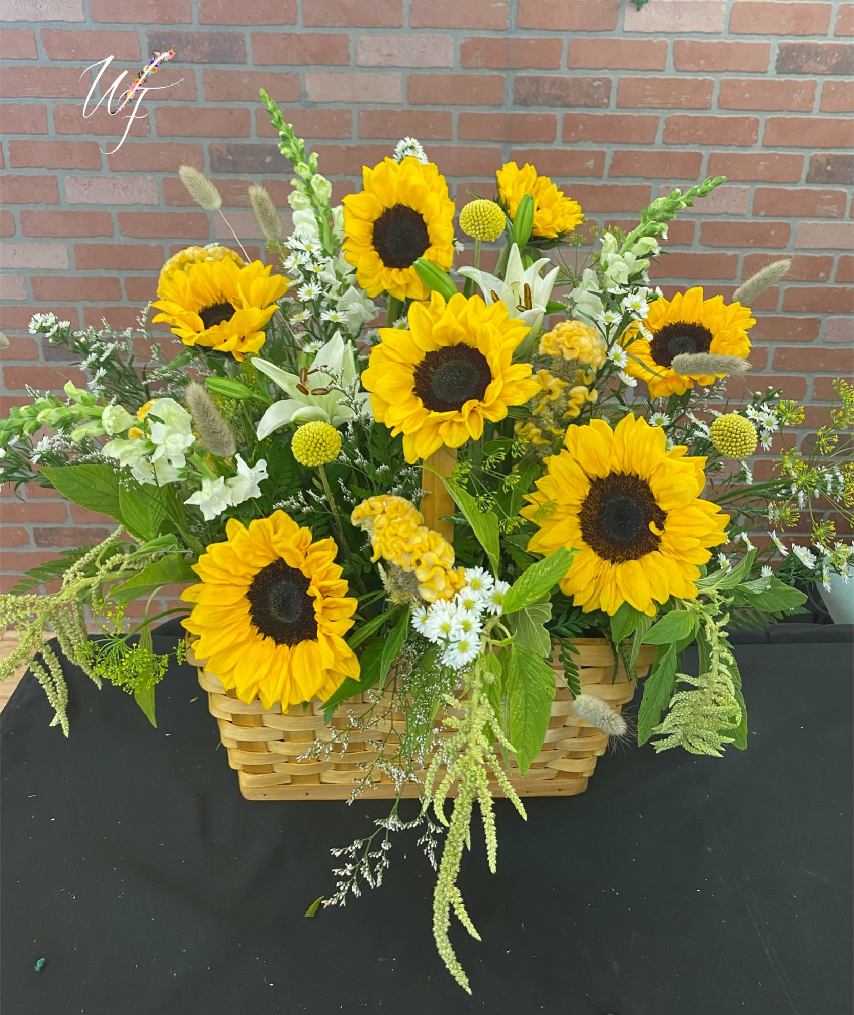 Basket arrangement with sunflowers and mixed white and green flowers