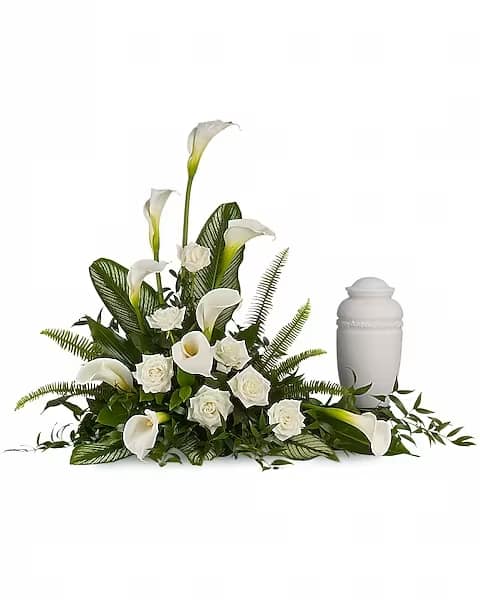 Stately Lilies - Cremation - "A calming portrait in ivory. Majestic calla lilies and stately white roses are framed by the lush leaves of aspidistra and calathea. Soft green sword fern adds to the soothing tones. Large white calla lilies pair with white roses and lush greens that include soft, airy sword fern and glossy aspidistra. Please note: Arrangement does not include urn."