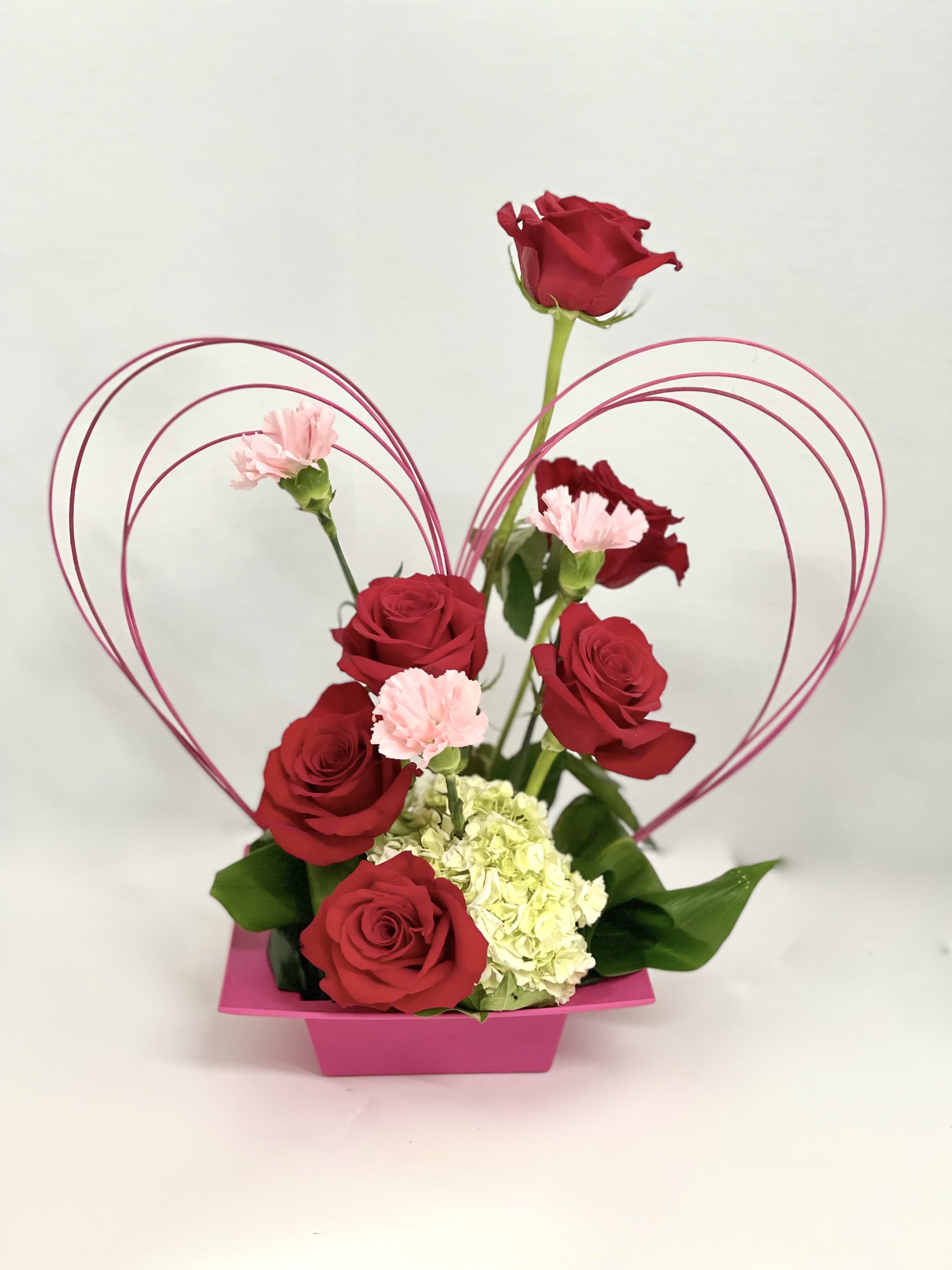 Red roses and pink carnations in a pink heart-shaped container