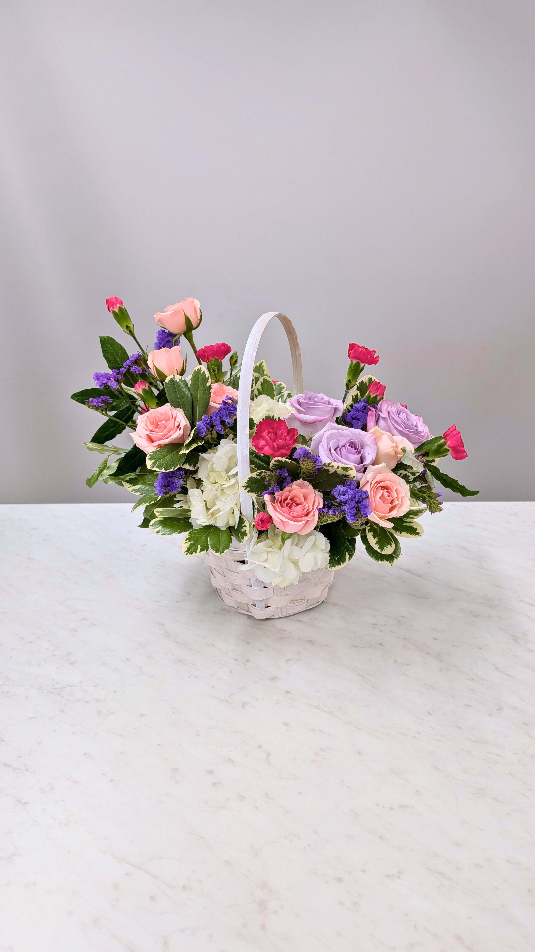 Basket o'Blooms - A sweet basket of colorful blooms, sure to brighten anyone's day! Show them you care with this cheerful basket arrangement.