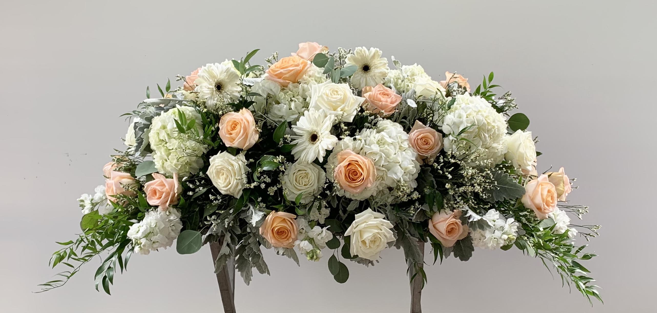 Large floral arrangement of peach and white roses with white blooms