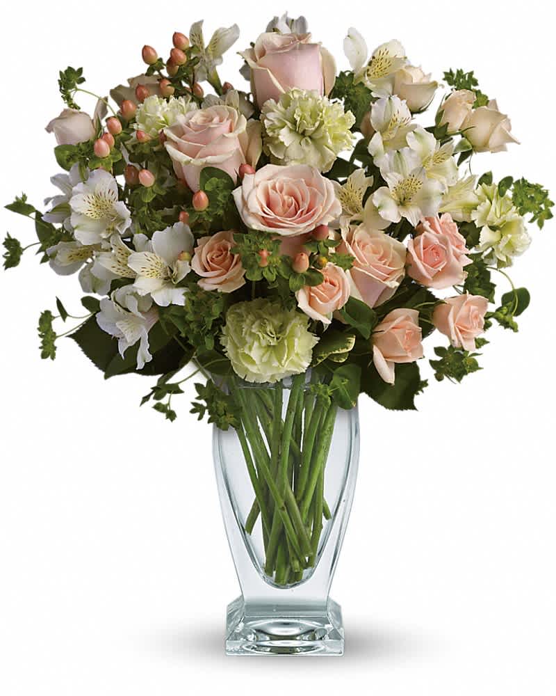 Arrangement of peach roses, green carnations, and white alstroemeria in a clear glass vase