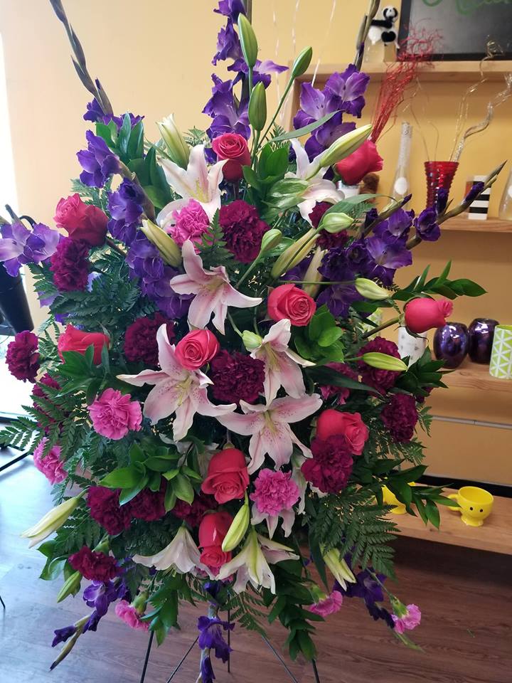 Large standing arrangement of pink roses, lilies, and purple flowers