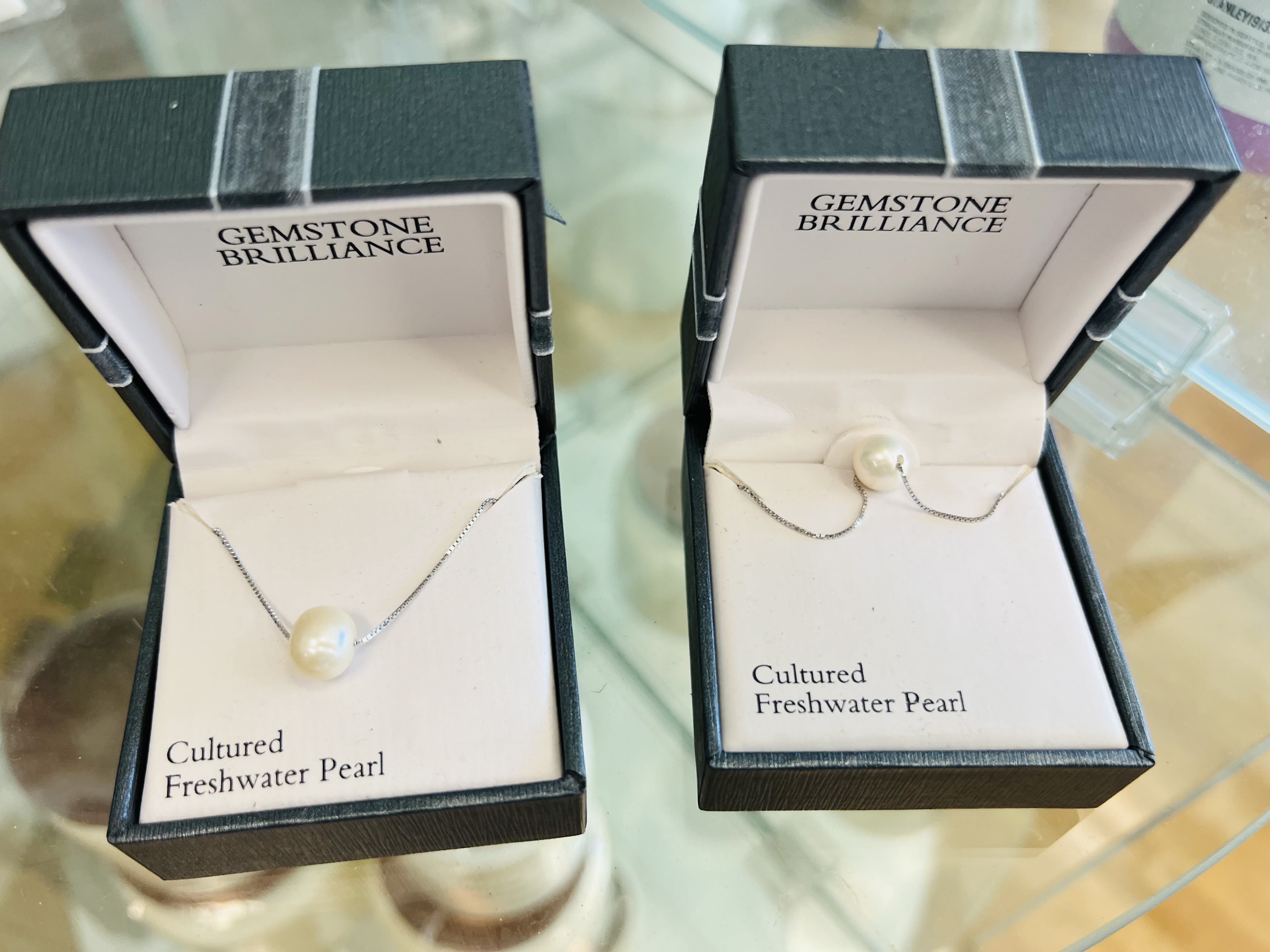 Two pearl necklaces in open jewelry boxes