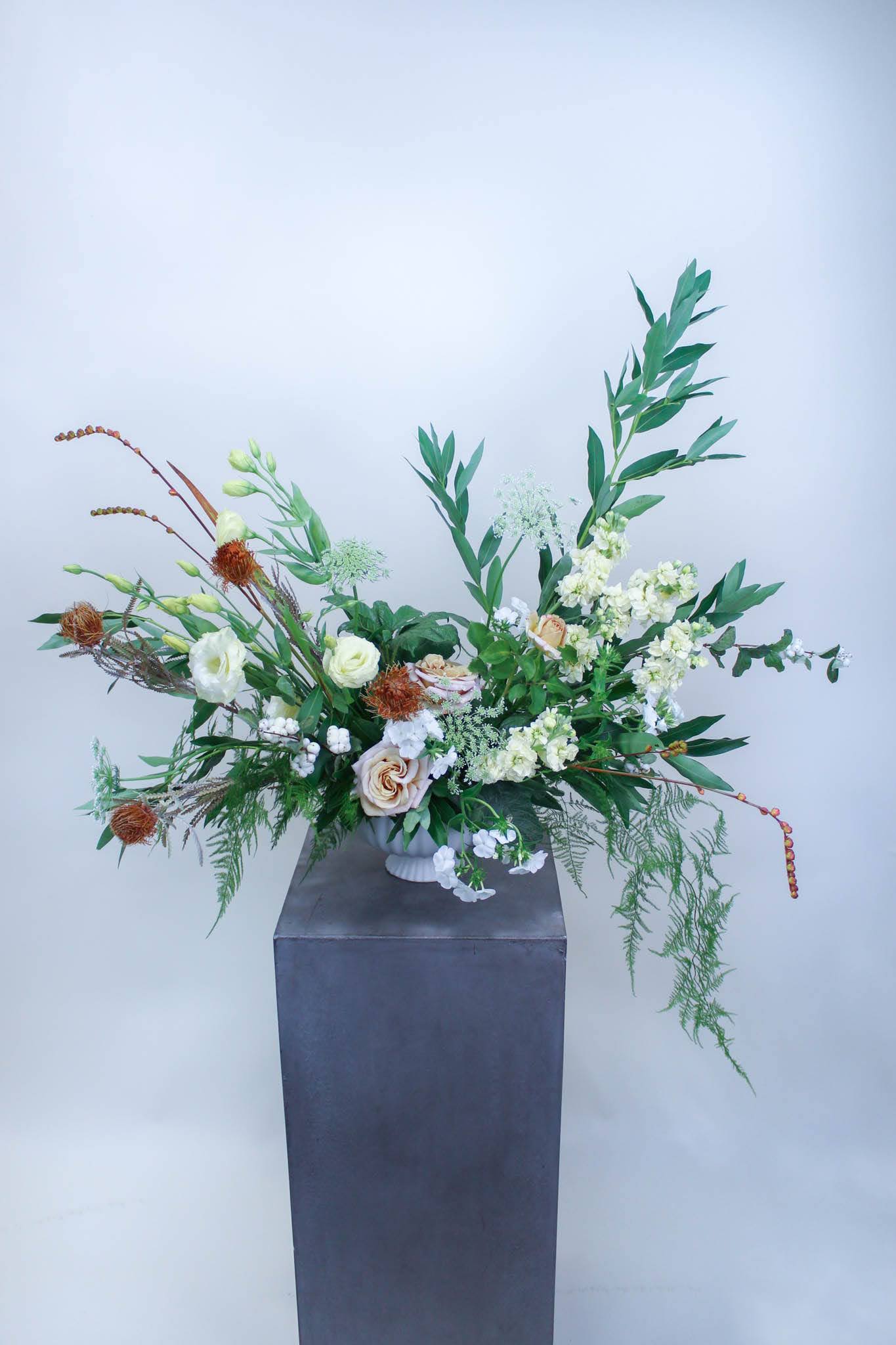 Large floral arrangement with white and peach blooms in a tall vase