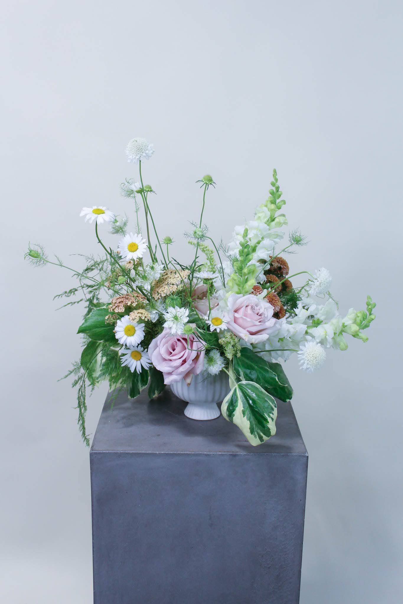 Pastel floral arrangement with pink roses and white daisies in a white vase