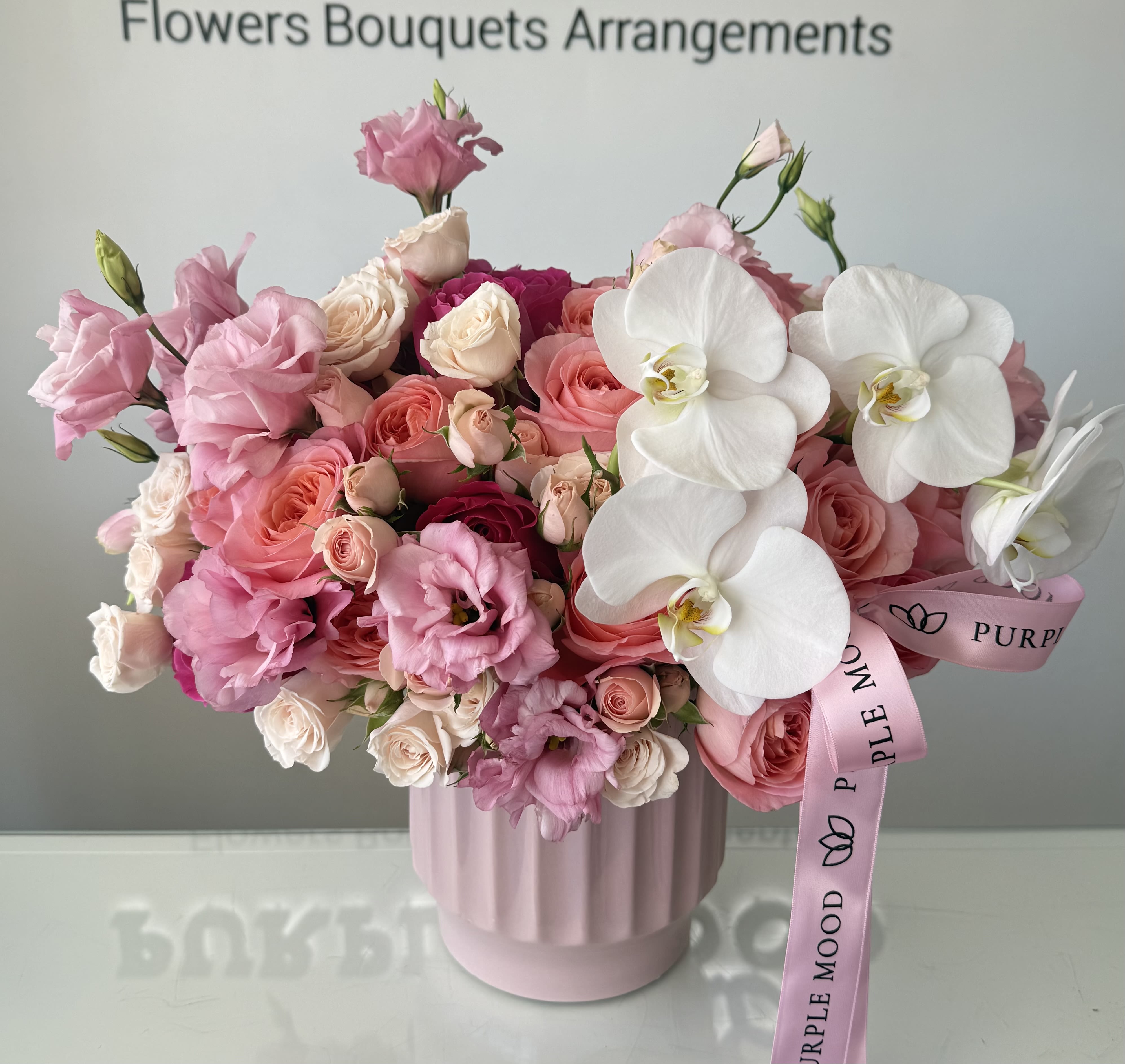 Bloom Vase - Bright, joyful, and bursting with color — our Bloom Vase is a stunning mix of fresh premium flowers accented with delicate seasonal fillers. Hand-arranged in an elegant textured vase and finished with a satin ribbon, this arrangement brings a lively, romantic charm to any occasion. Perfect for birthdays, anniversaries, or simply to brighten someone’s day.    •    Premium flowers in mixed shades (hot pink, blush, cream)     •    Accented with seasonal fillers for texture and fullness     •    Presented in a stylish vase with satin ribbon finish     •    Represents joy, romance, and celebration     •    Perfect for birthdays, anniversaries, or special surprises