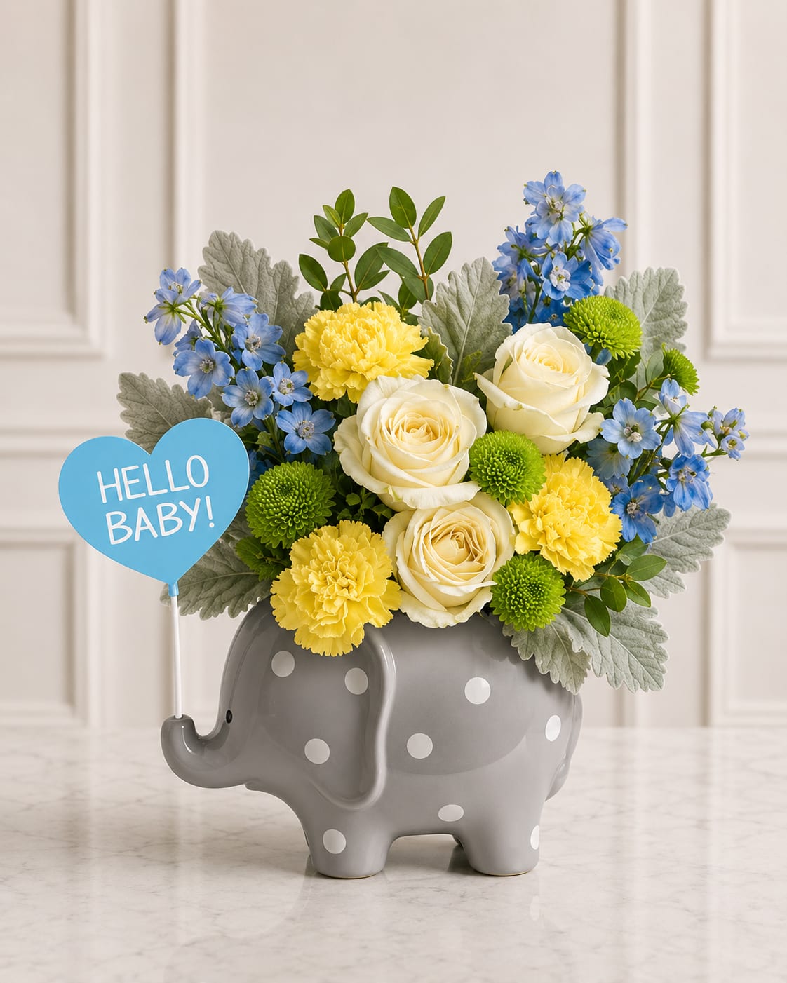 Bouquet of blue, yellow, and white flowers in a gray elephant vase with a "Hello Baby!" sign