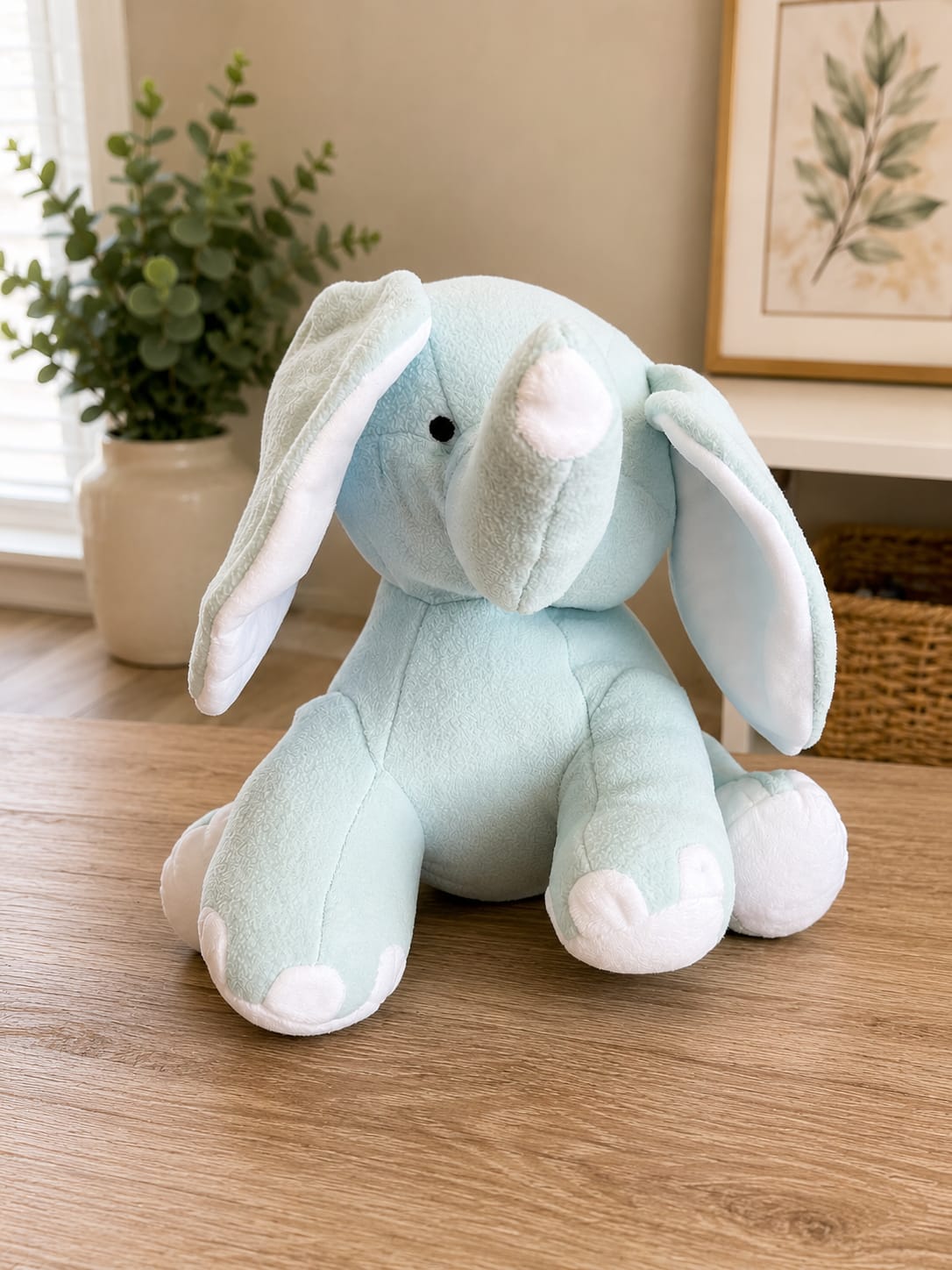 Baby Blue Cuddly Elephant - A pale blue cuddly bunny takes center stage in this baby gift arrangement, perfect for a newborn celebration or a sweet baby shower surprise. The gentle blue and white palette reads as calm and comforting, making this nursery-friendly gift a thoughtful way to welcome a new little one or to say congratulations to new parents.  Soft textures and simple color harmony define the piece: a plush pale-blue bunny with white ear and paw accents is paired with coordinating blue, white, and green florals (and foliage) to create a peaceful, balanced look. The arrangement sits upright and is sized to be display-ready on a dresser or nursery shelf; the compact silhouette keeps it easy to place while still feeling substantial.  For a new baby, new-parent pick-me-up, or cheerful everyday gift, this is the kind of present that helps the recipient feel loved and seen. Gentle care: keep the plush and flowers away from direct sunlight and dampness to preserve colors and softness; order early to ensure timely delivery for shower dates and welcome-home moments.