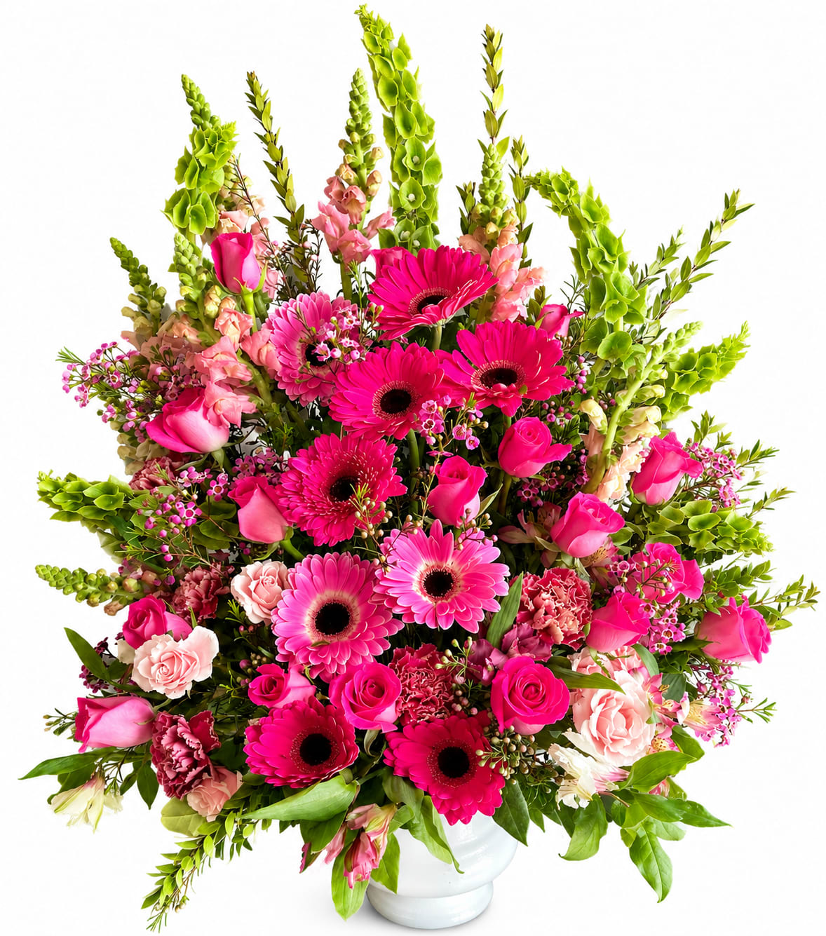 Forever by Our Side - Hot pink gerbera daisies and soft pink roses take center stage in this vibrant sympathy flower arrangement, offering a hopeful, uplifting presence for a funeral or times when you want someone to feel comforted and remembered. The mix reads as both celebratory and reassuring-perfect for expressing sympathy, sending condolences, or brightening a difficult day with a warm, caring message.  A generous, rounded base of pale blush carnations and lush greenery supports tall lime-green snapdragon-like spikes that rise above the bouquet, adding height and a lively vertical accent. Arranged in a sleek white ceramic vase, the contrasting hot pinks and vivid greens create an energetic yet tasteful palette; the piece is large and full with dramatic lines that make it visible in a gathering or on a memorial table.  This arrangement is an elegant way to say you're thinking of them-whether for a funeral service or to send sympathy at home. The ceramic vase provides stable display; trim stems and change the water every few days to help blooms last longer.