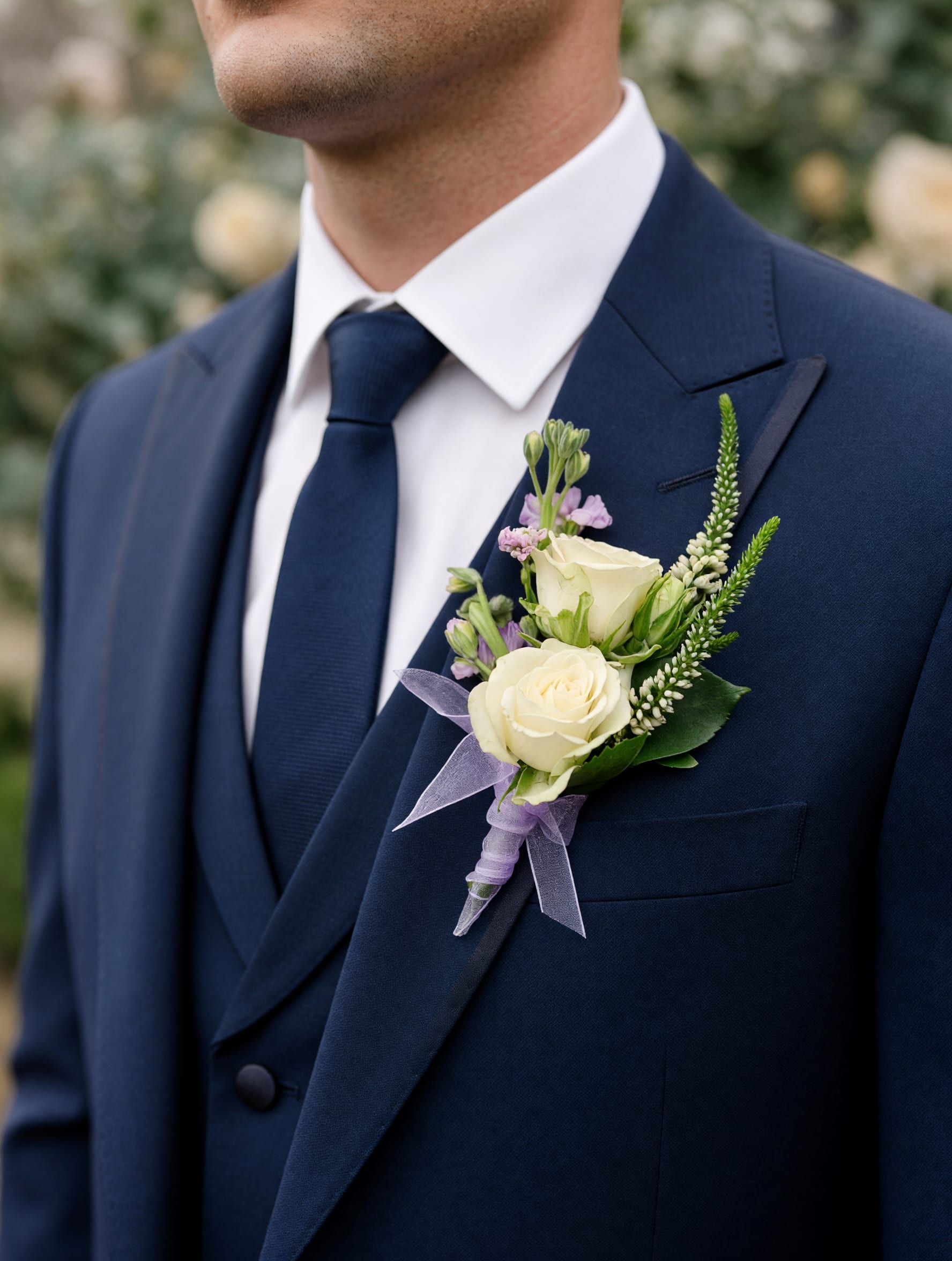 Classic White Boutonniere - A timeless white boutonniere featuring a fresh white bloom accented with complementary greenery. Handcrafted for weddings, proms, and other special occasions, this elegant floral accent adds a classic finishing touch to any suit or tuxedo.