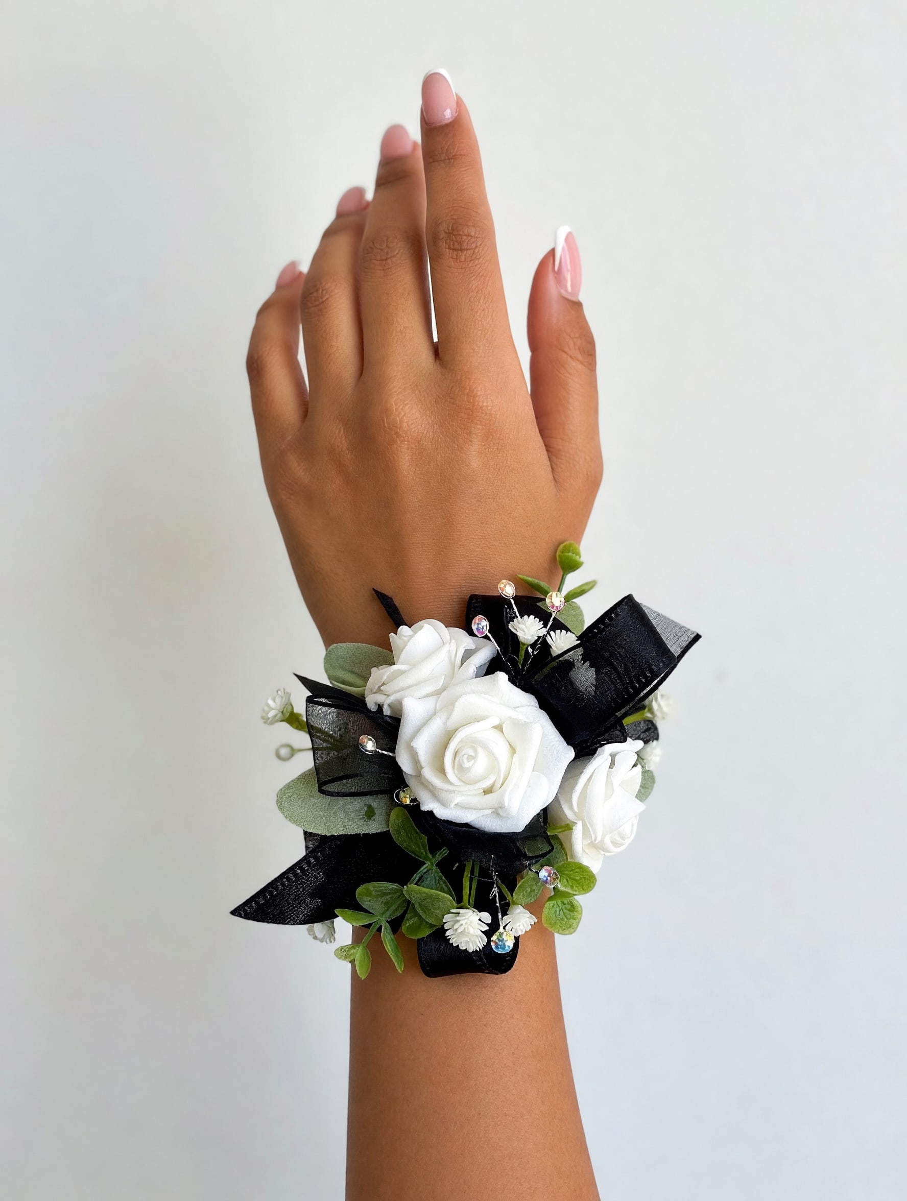 Classic White Spray Rose Wrist Corsage - A sophisticated wrist corsage featuring fresh white spray roses, elegant black ribbon, sparkling rhinestone accents, and a coordinating rhinestone bracelet. Handcrafted for weddings, proms, homecoming, and other special occasions, this timeless design adds a refined and elegant finishing touch to any outfit.