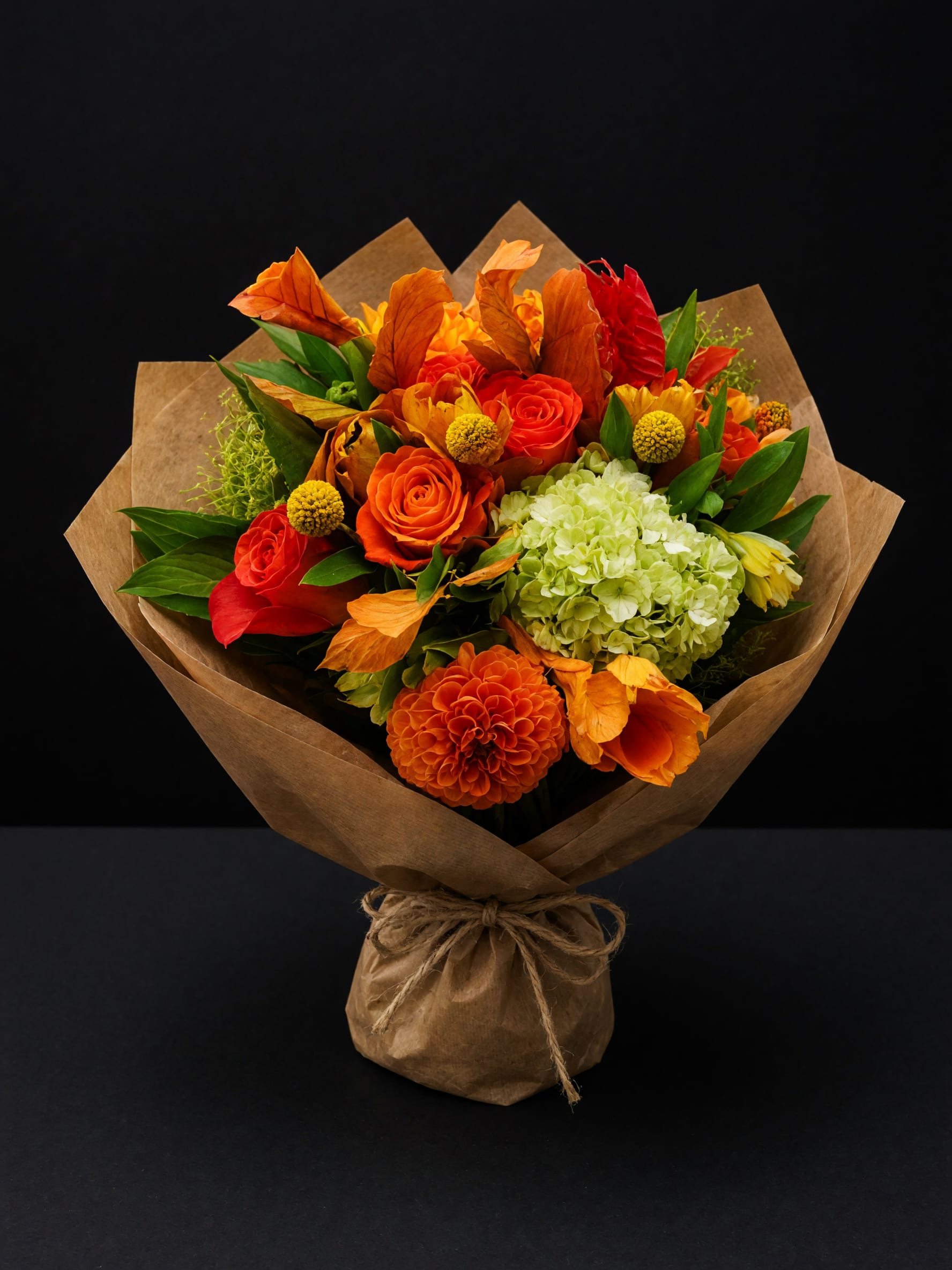 Bouquet of orange and red flowers wrapped in brown paper