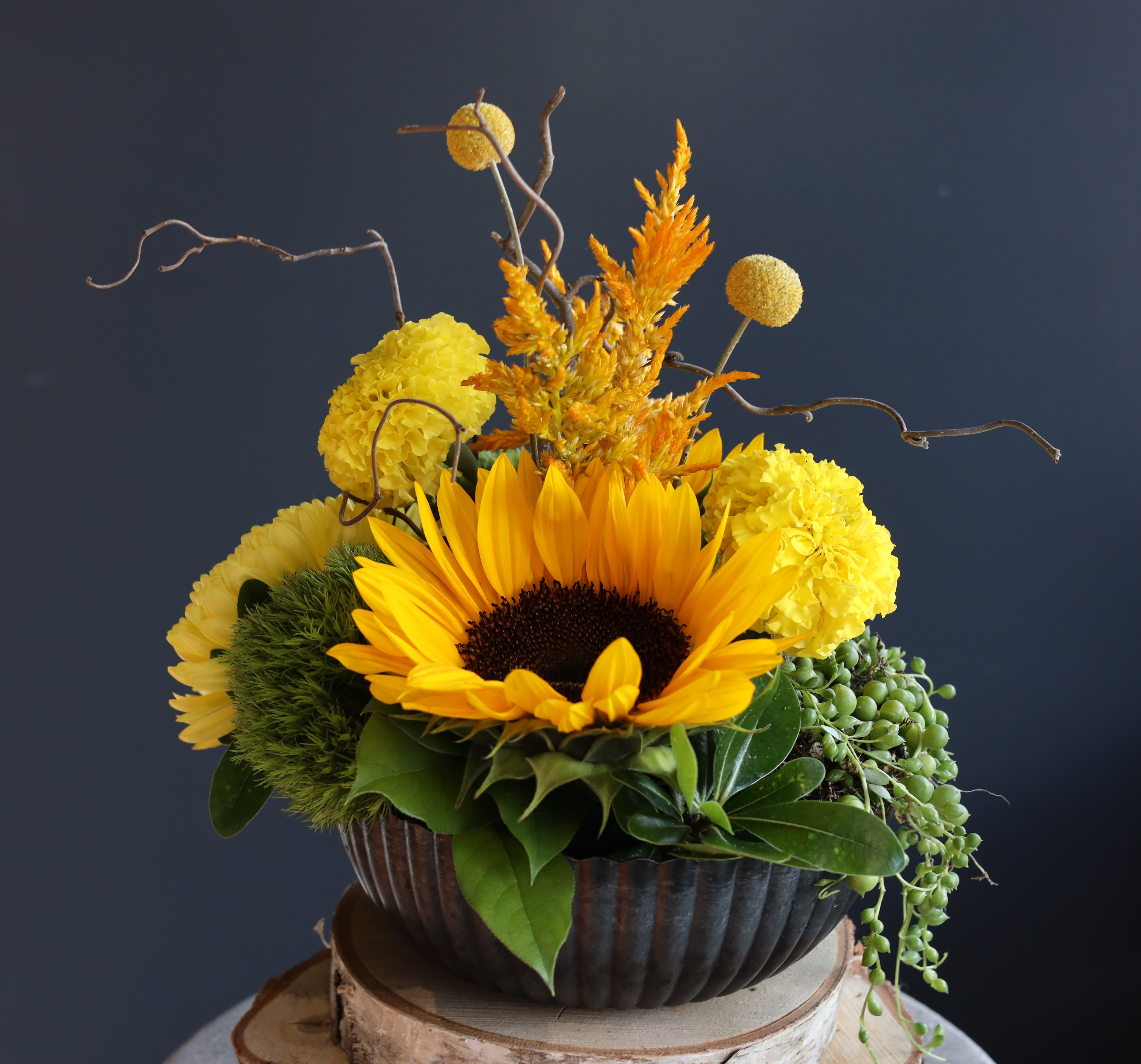 Sunflower arrangement with yellow blooms in a dark bowl vase