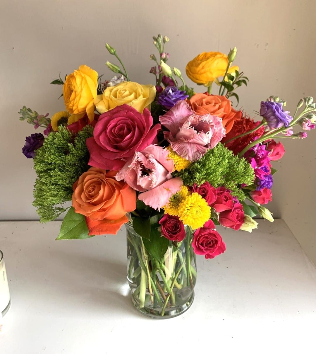 Colorful mixed bouquet of roses and other blooms in a clear glass vase