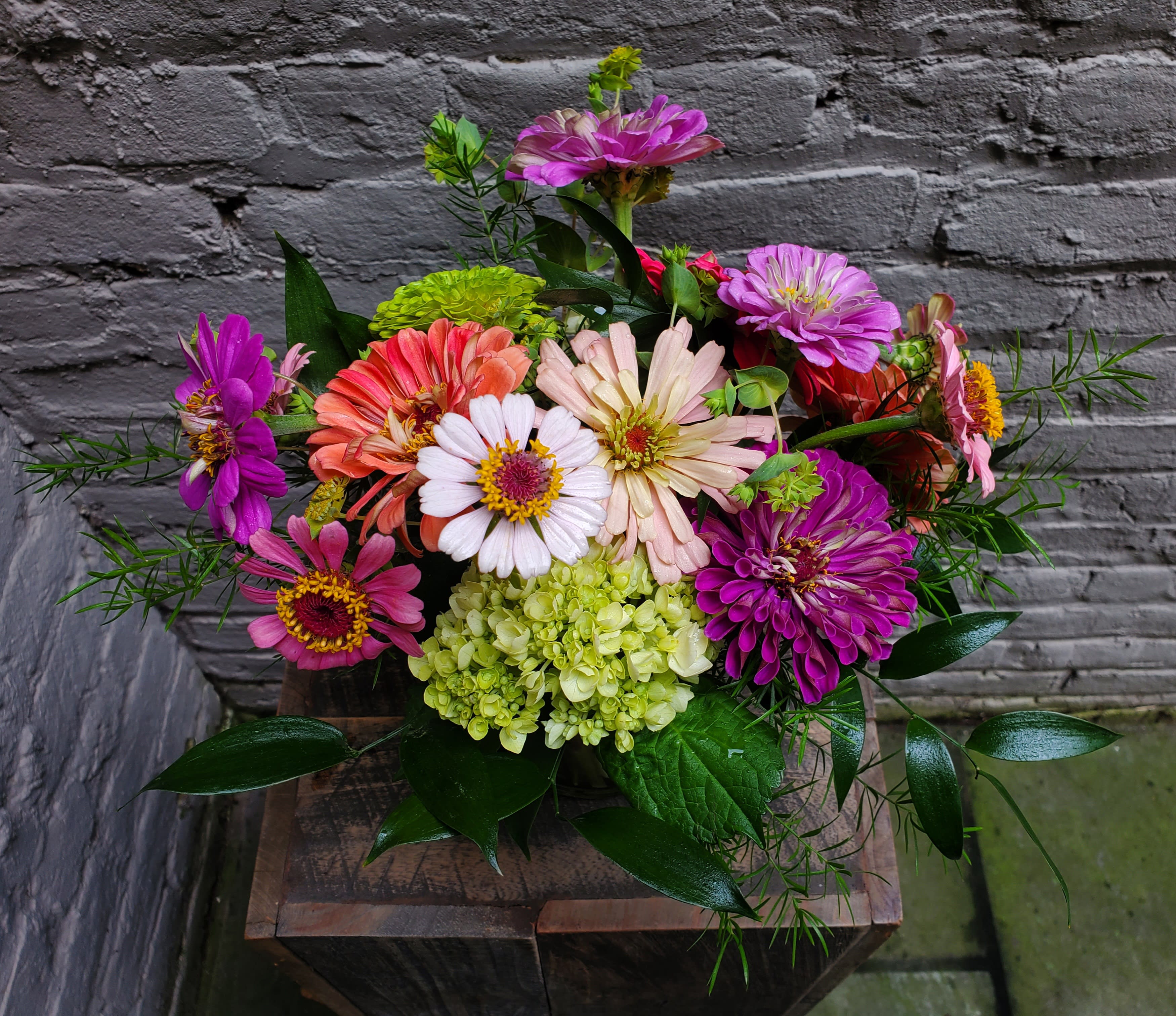 Colorful mixed bouquet of zinnias and hydrangea in a rustic container